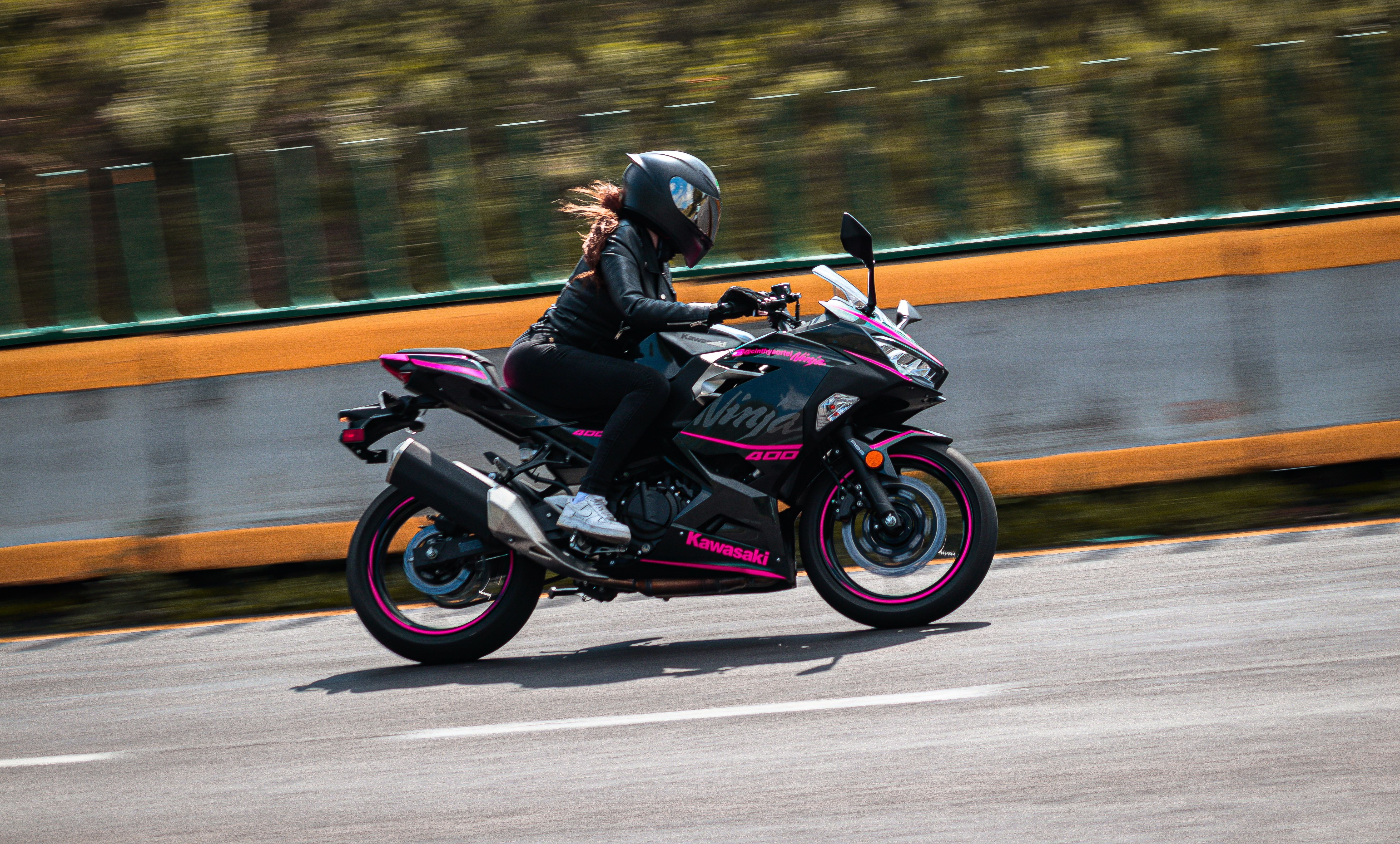 Woman riding black and pink Kawasaki Ninja 400 