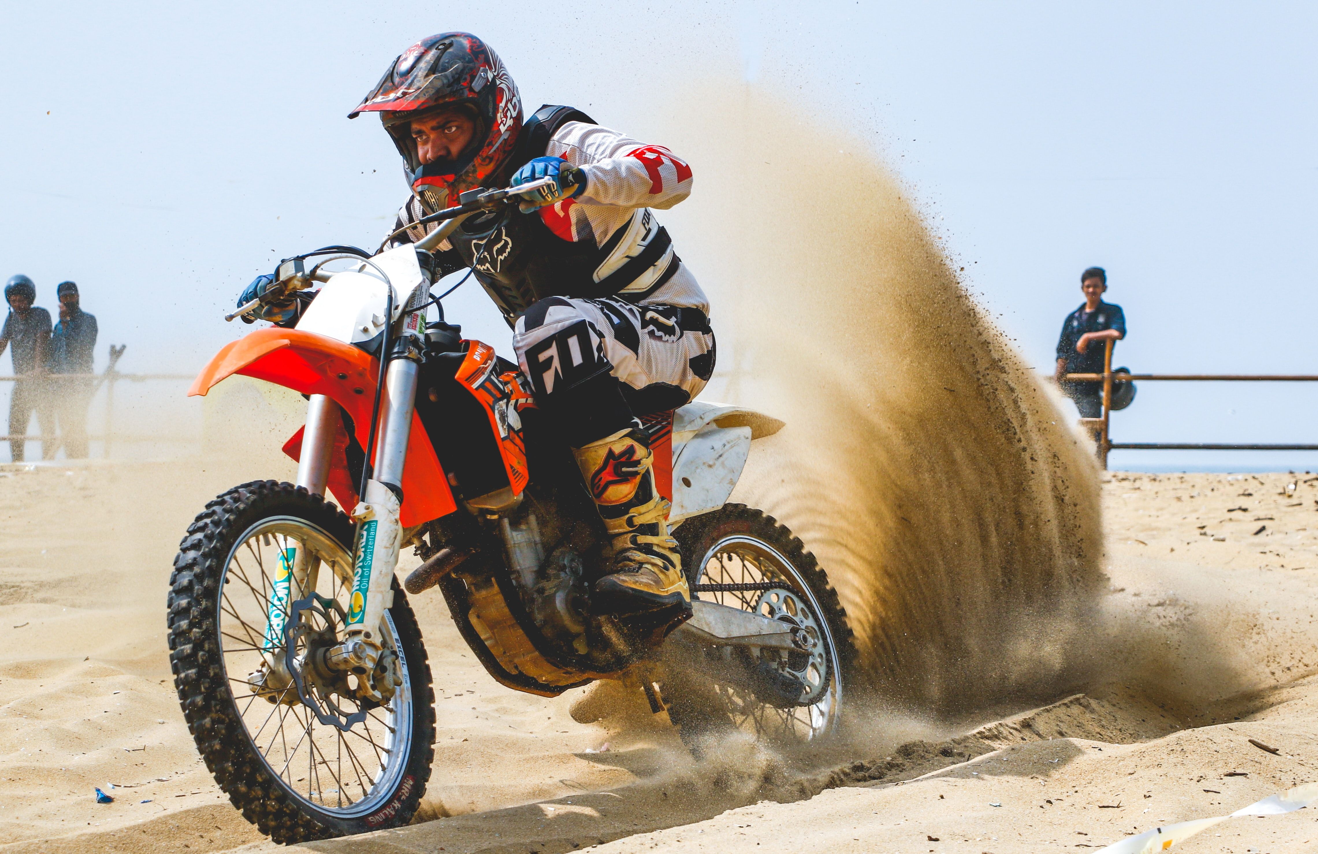 Man riding KTM dual sport motorcycle in sand. 