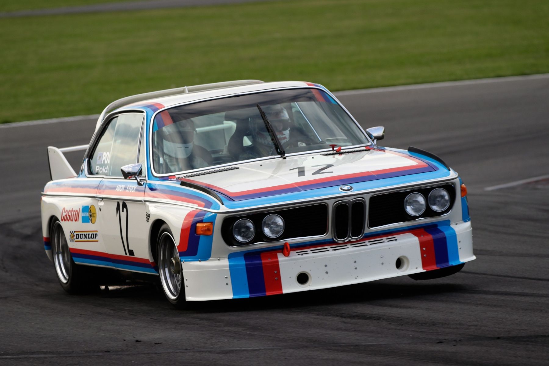 A dynamic front three-quarters dynamic shot of the original E9 BMW 3.0 CSL on a racetrack. 