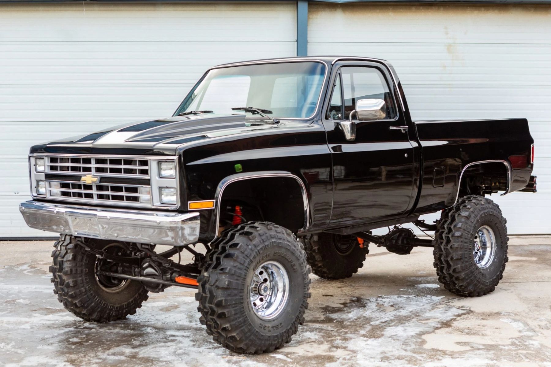 A front three-quarters static shot of a black modified 1987 Chevrolet K10 pickup.