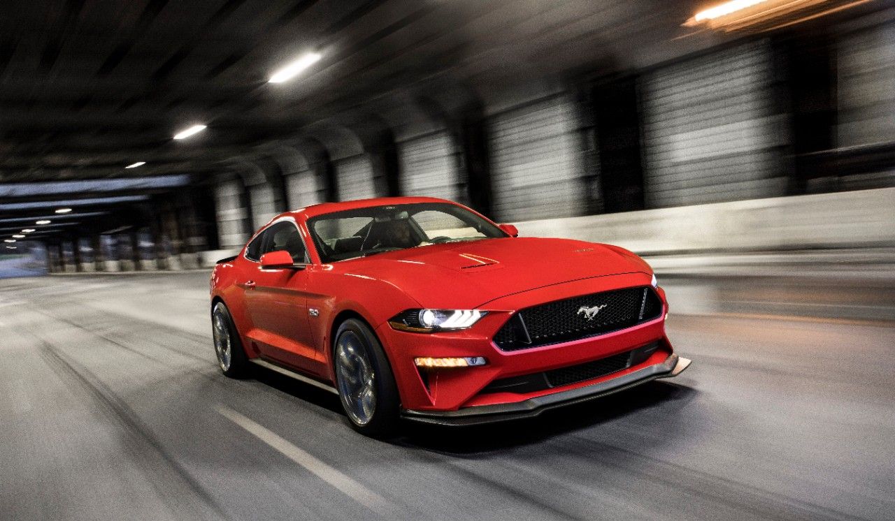 Front three-quarter shot of a red Ford Mustang GT driving through a tunnel. 