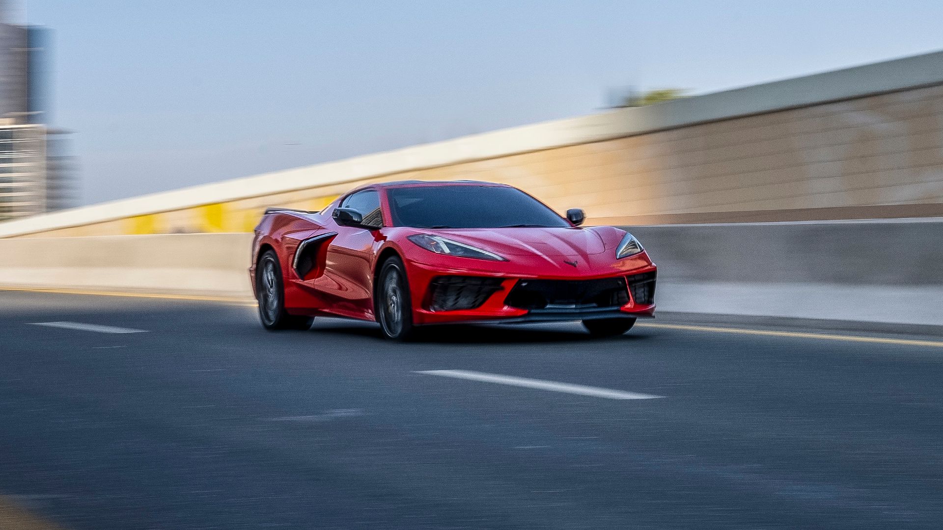 A front three-quarters shot of a red 2023 Chevrolet Corvette Stingray driving on a road. 