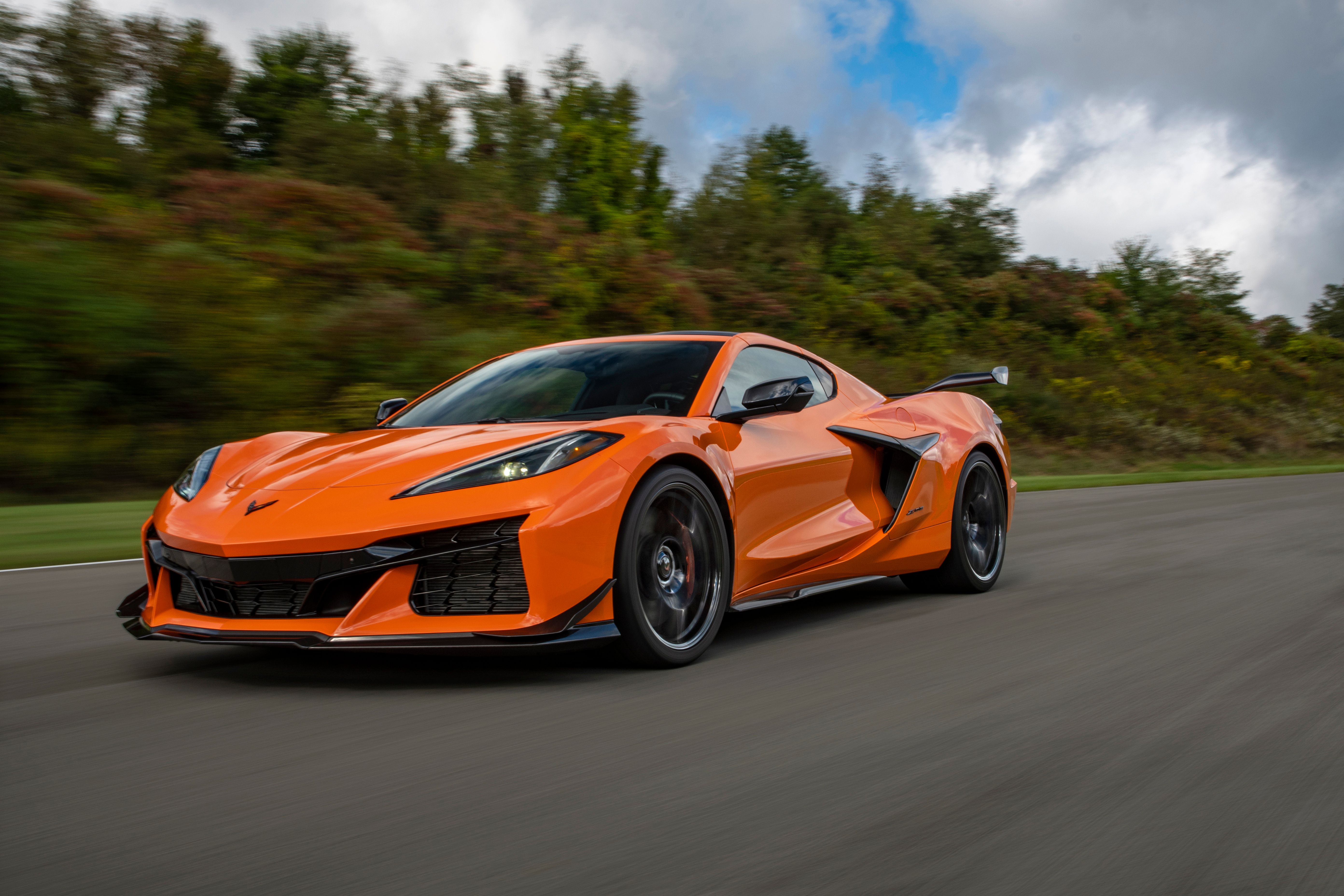 Uma foto frontal de três quartos de um Corvette Z06 2023 laranja dirigindo em uma estrada. 