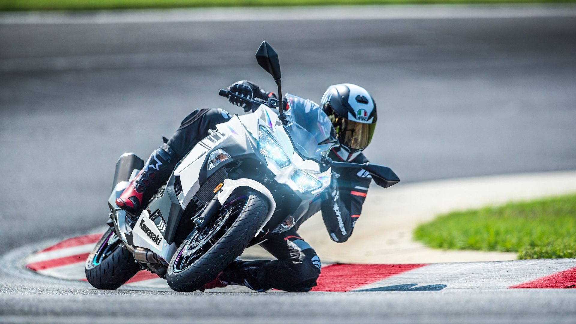 Rider dragging a knee on a white 2023 Kawasaki Ninja 400