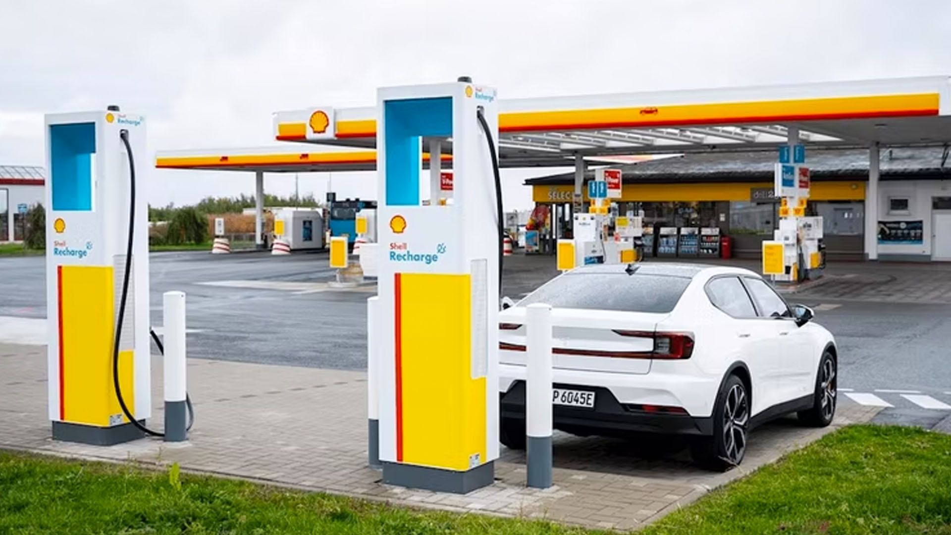 A pair of shell recharge charging stations with a car plugged in.