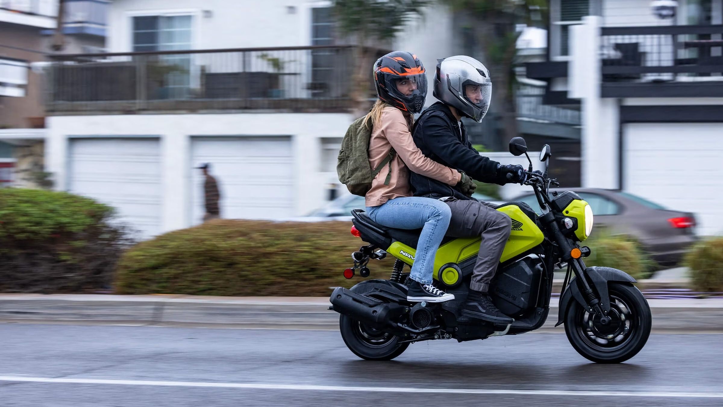 A side action shot of a 2022 Honda Navi carrying rider, and pillion