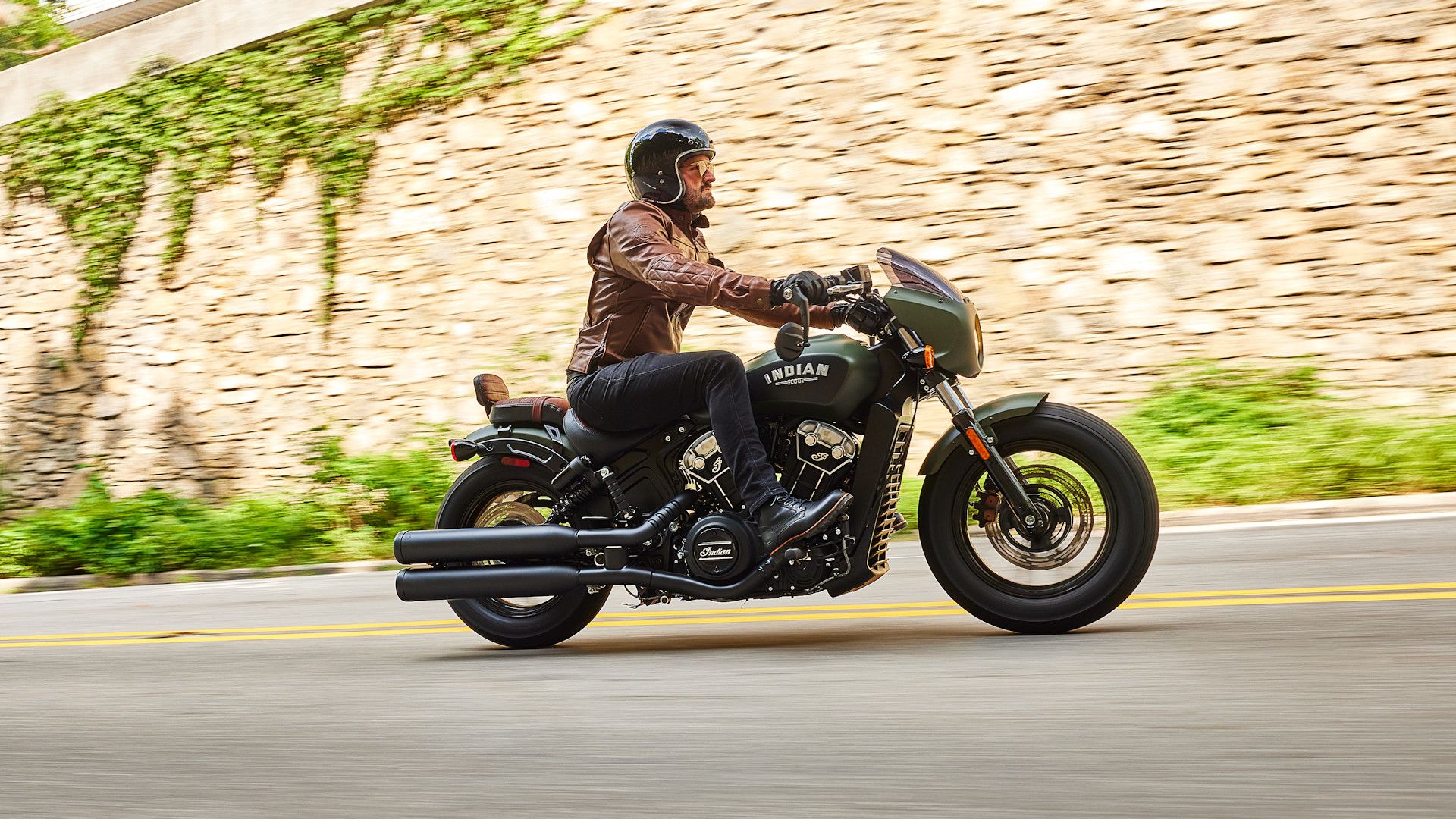 Accessorized green 2023 Indian Scout Bobber cruising on the road