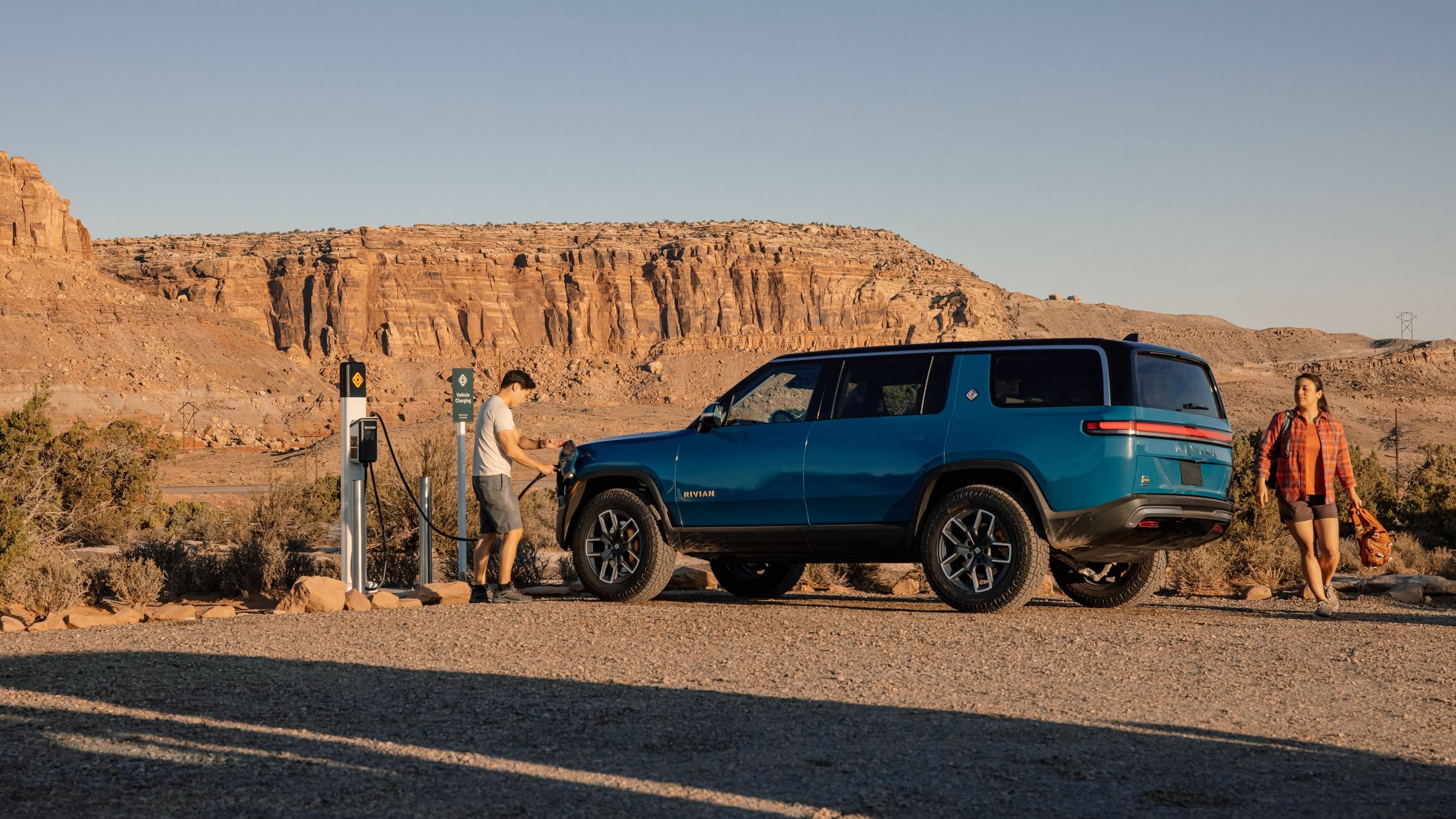 A shot of a blue Rivian R1S being charged 