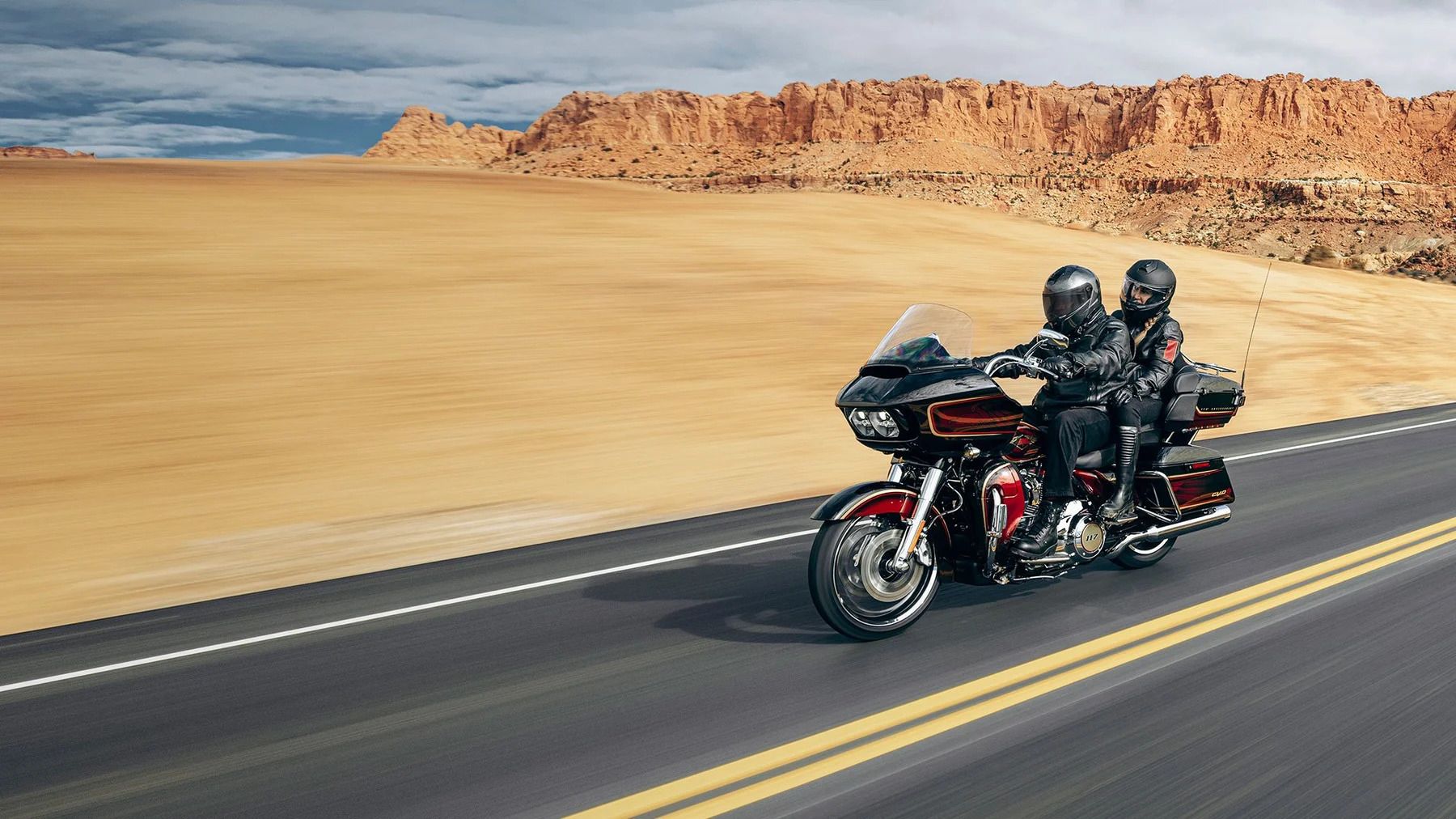 An action shot of a 2023 CVO Road Glide Limited Anniversary Edition riding two up on the road