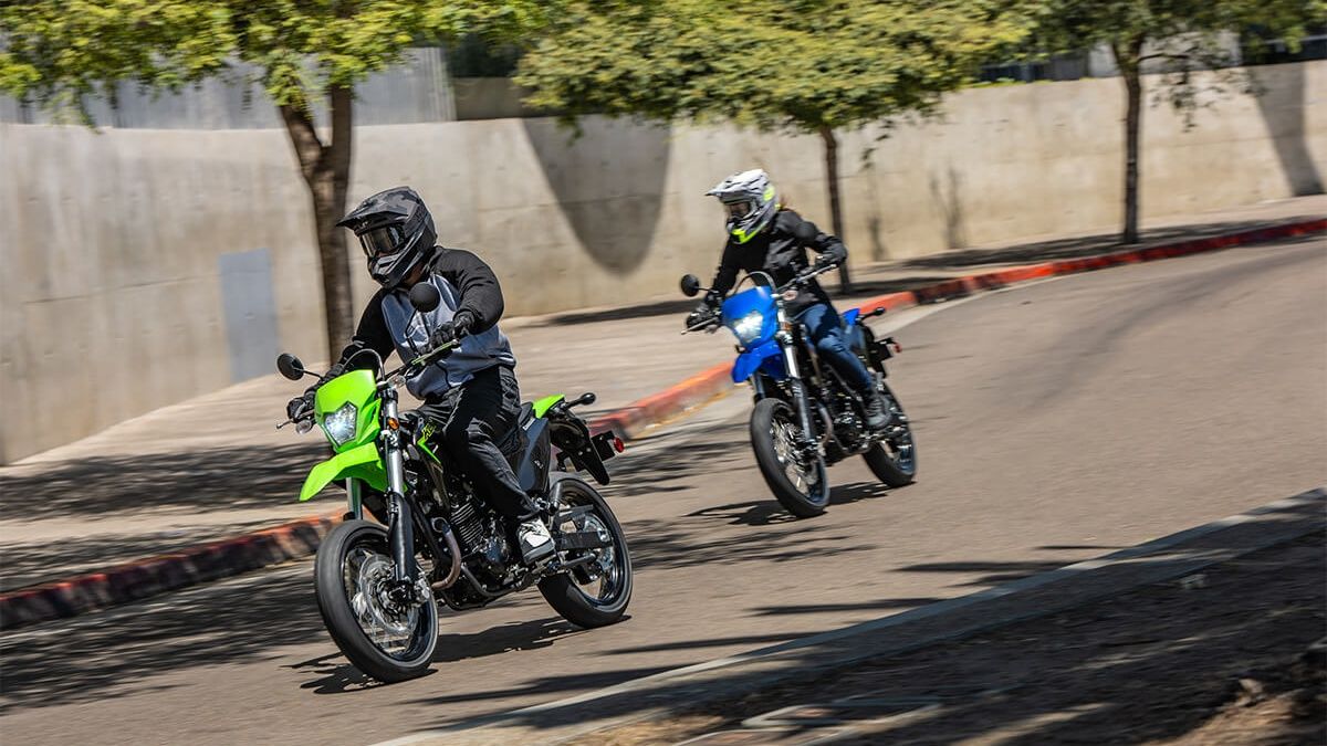 A front action shot of two KLX230SM riding on the street