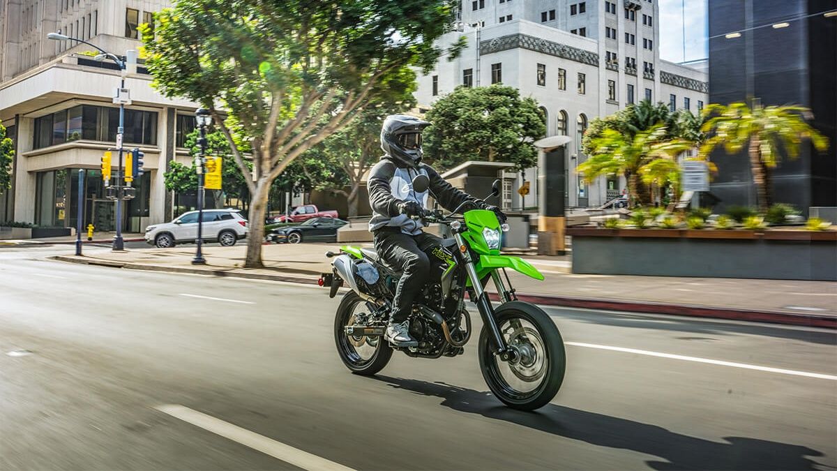 A front 3/4 action shot of a 2023 Kawasaki KLX230SM riding on the street