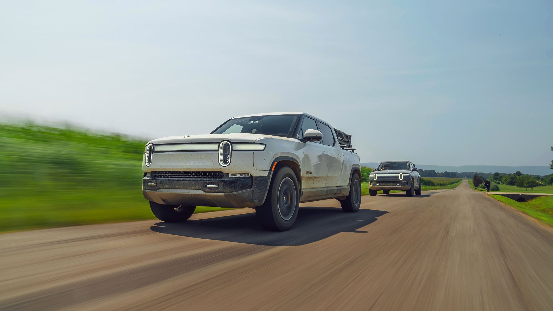 Rivian R1T driving in front of another Rivian EV