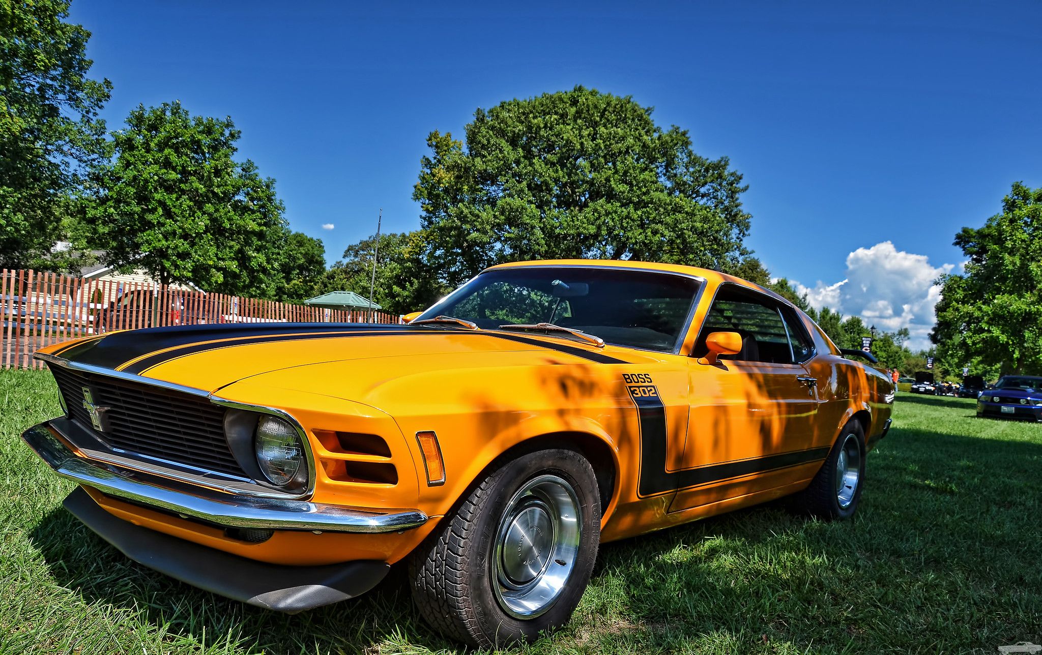 1970 Ford Mustang Boss amarelo 302 em frente à cerca em dia ensolarado