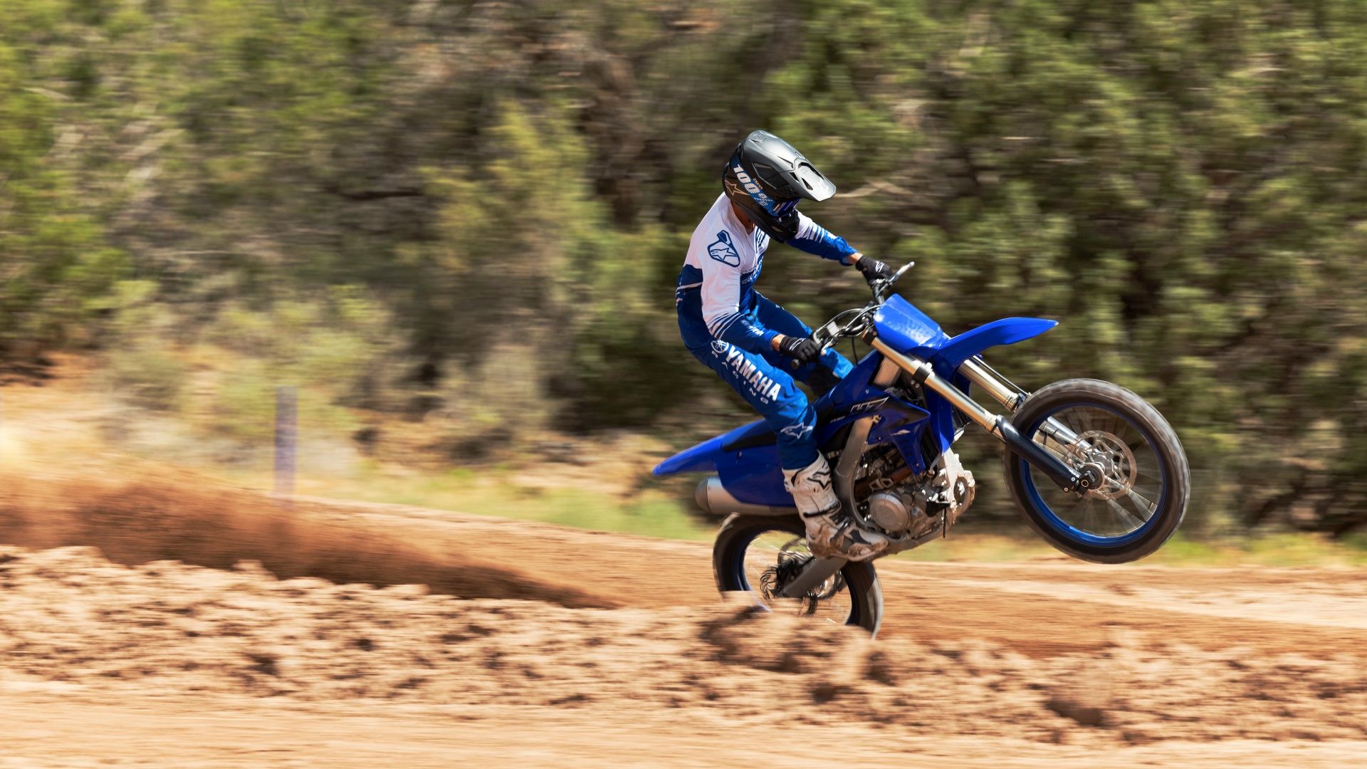 An action shot of a 2023 YAMAHA YZ450F wheeling on the dirt track