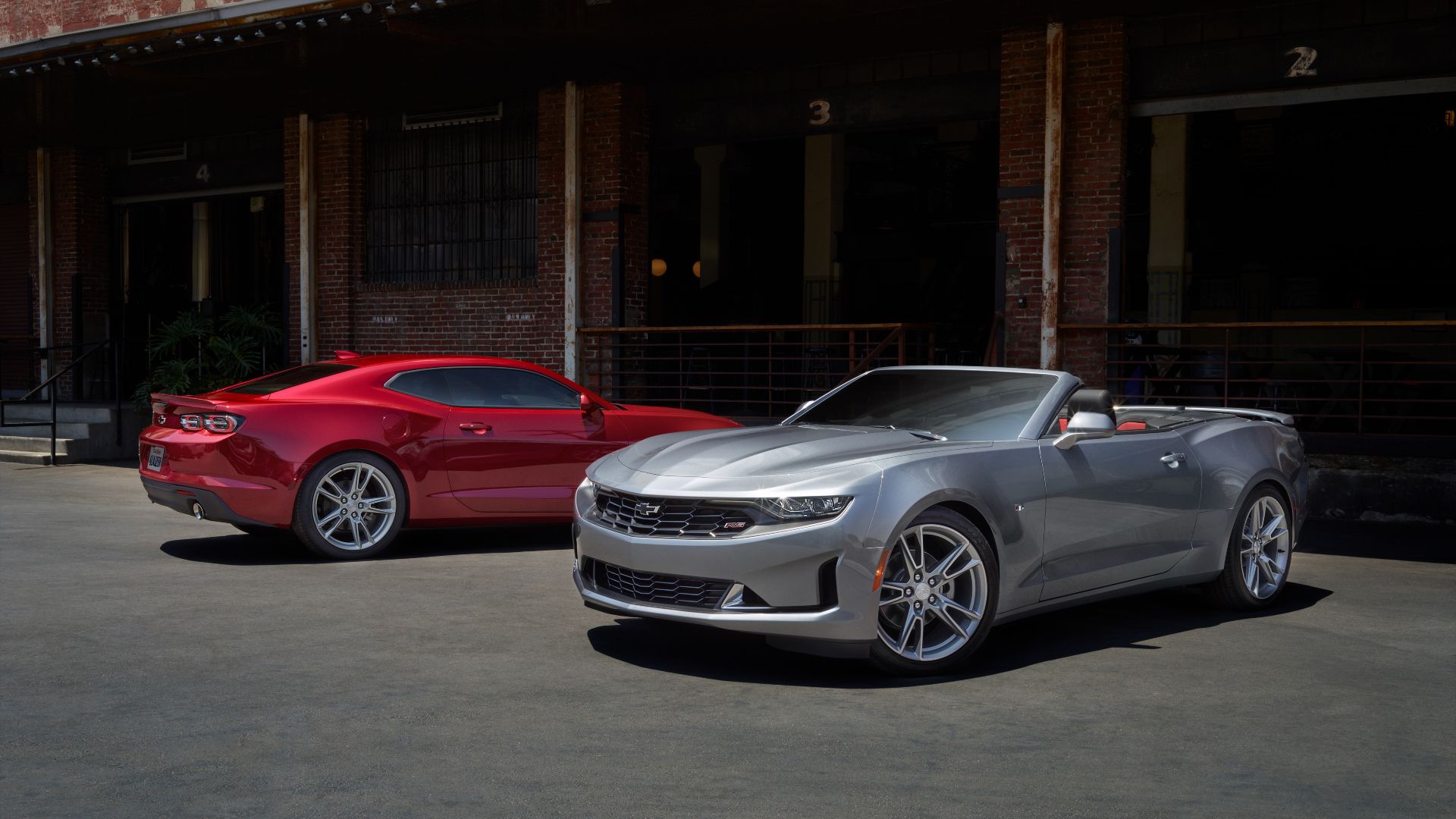 Um Camaro 2023 conversível prateado com um Camaro cupê 2023 voltado para trás.