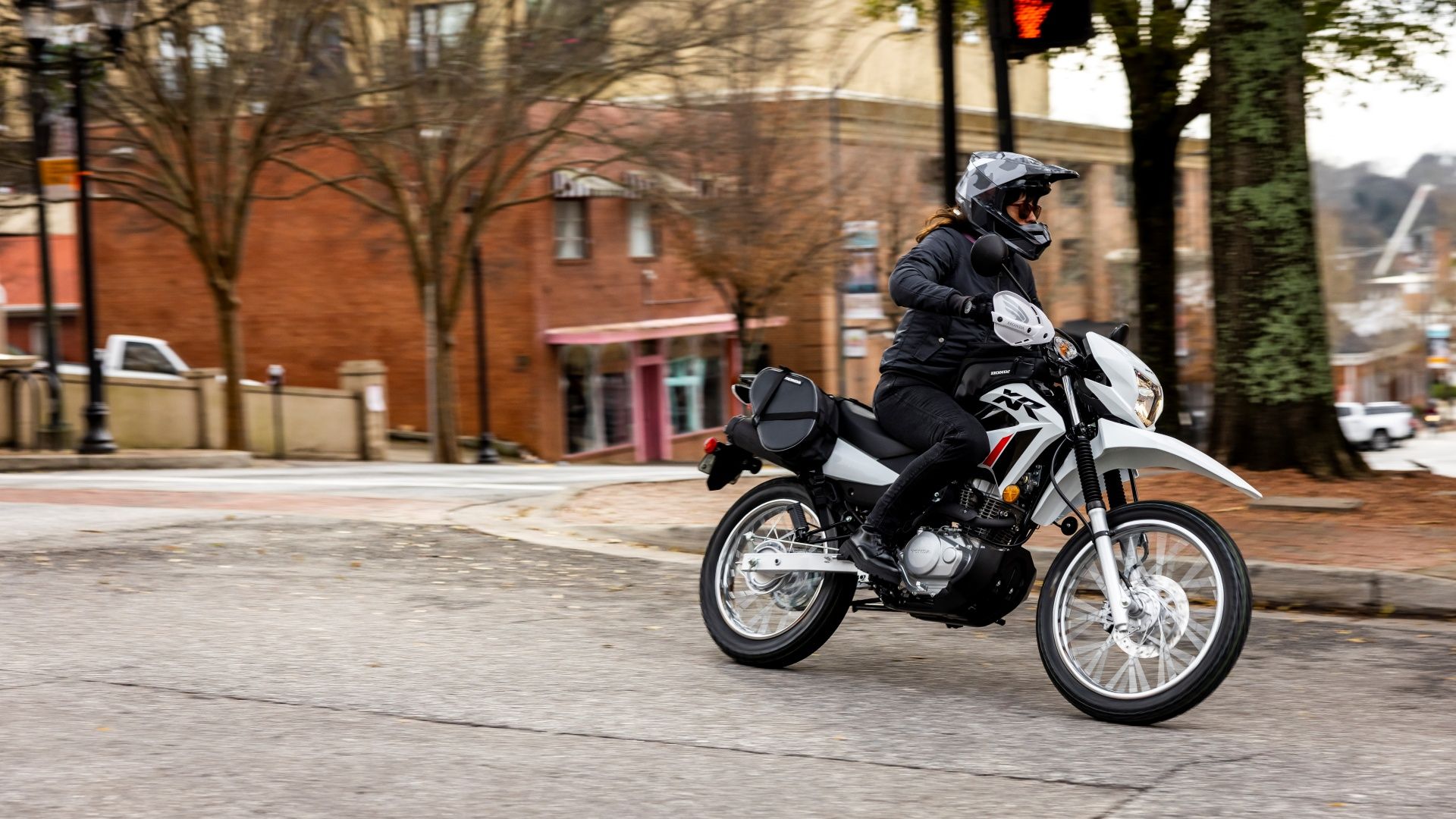 An action shot of a 2023 Honda XR150L riding on the street