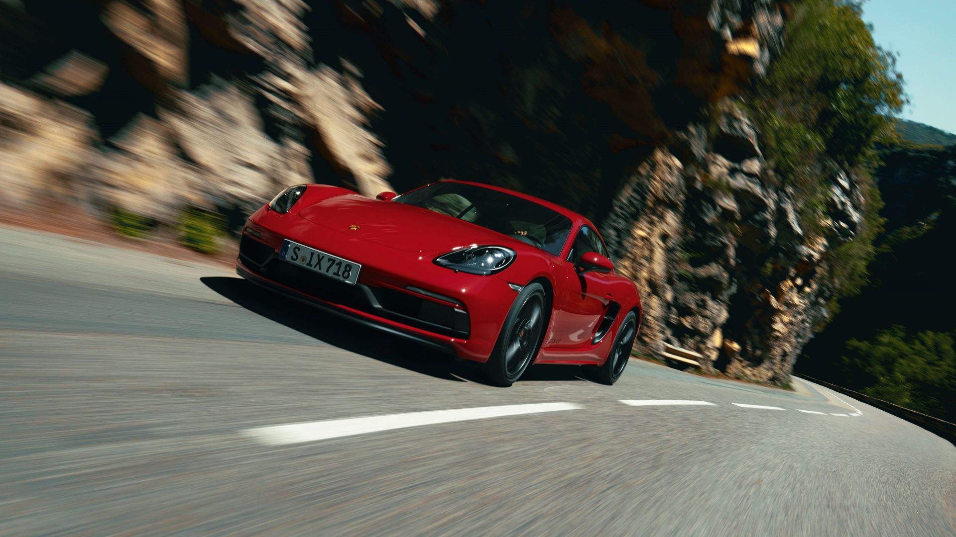 An action front 3/4 shot of a red Porsche 718 Cayman GTS 4.0 on the road