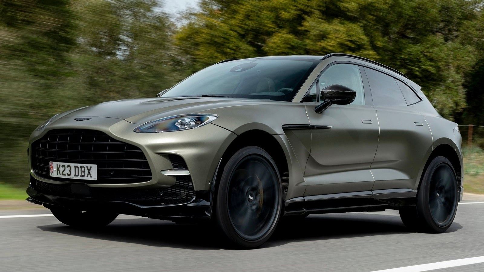 Front 3/4 view of 2023 Satin Titanium Grey Aston Martin DBX707 driving. 