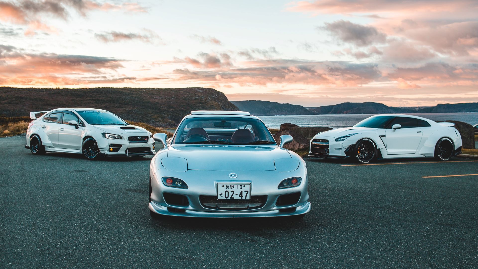 A shot depicting a Mazda RX-7, Nissan GT-R, and Subaru WRX parked