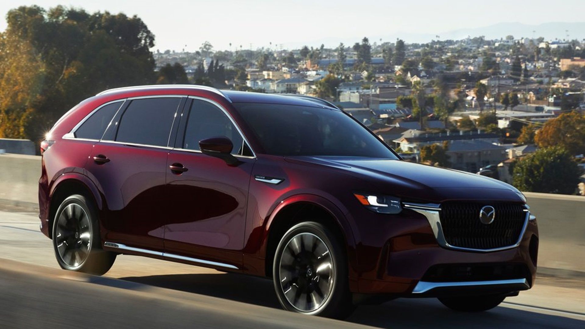 Front three-quarter shot of an Artisan red Mazda CX-90 in motion