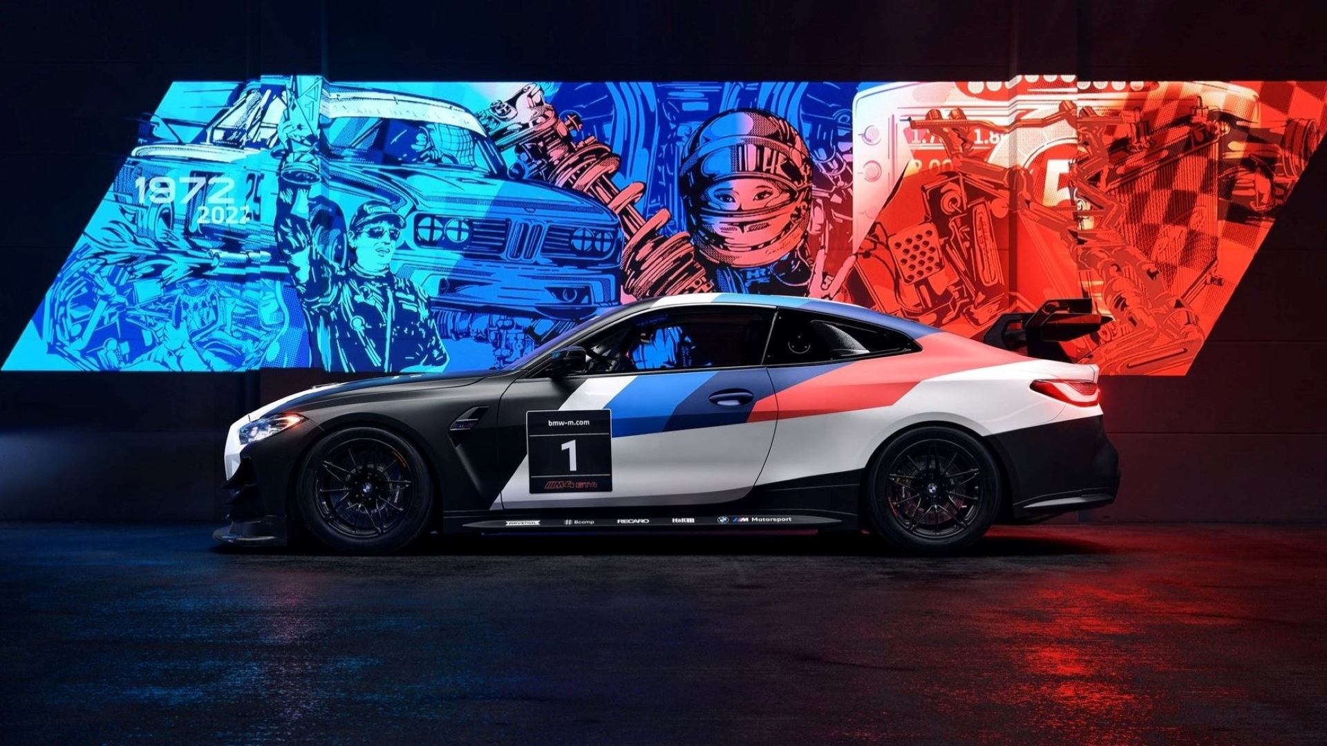 Vista lateral de um BMW M4 GT4 2023 em frente a um mural usando cores M