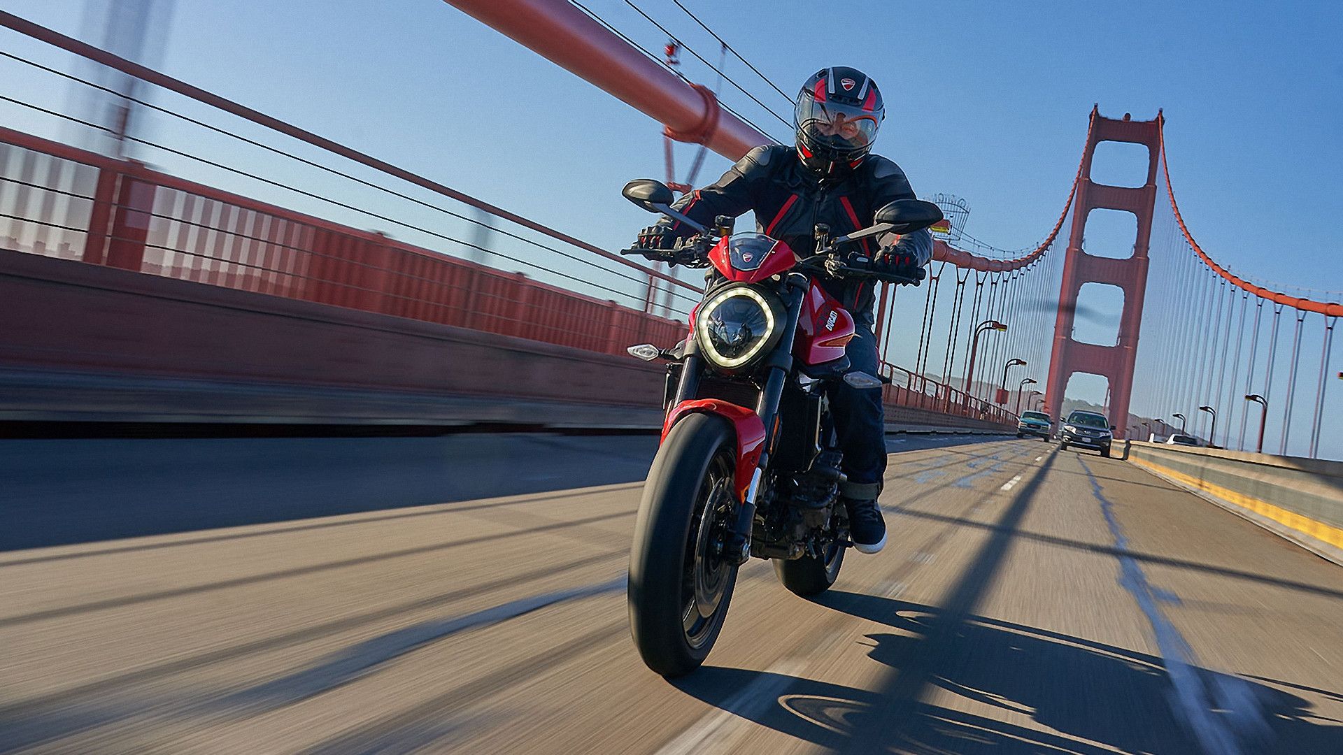 Red 2024 Ducati Monster 937 Plus cruising over a bridge