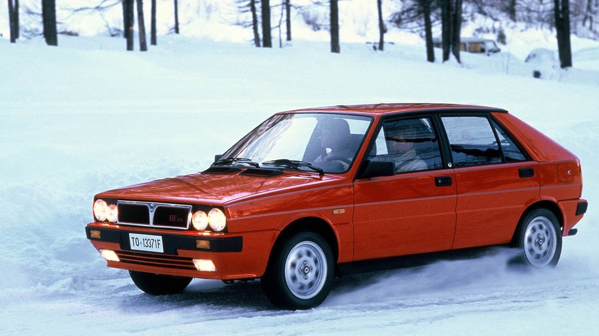 Uma foto frontal 3/4 de um Lancia Delta HF 4WD 1986 caminhando pela neve