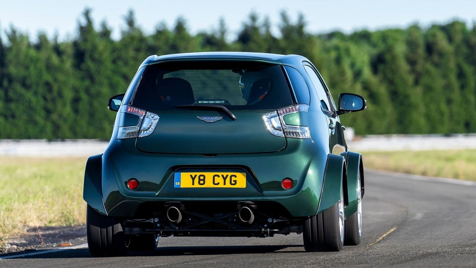 Vista traseira de um Aston Martin V-8 Cygnet verde fazendo curvas em uma pista