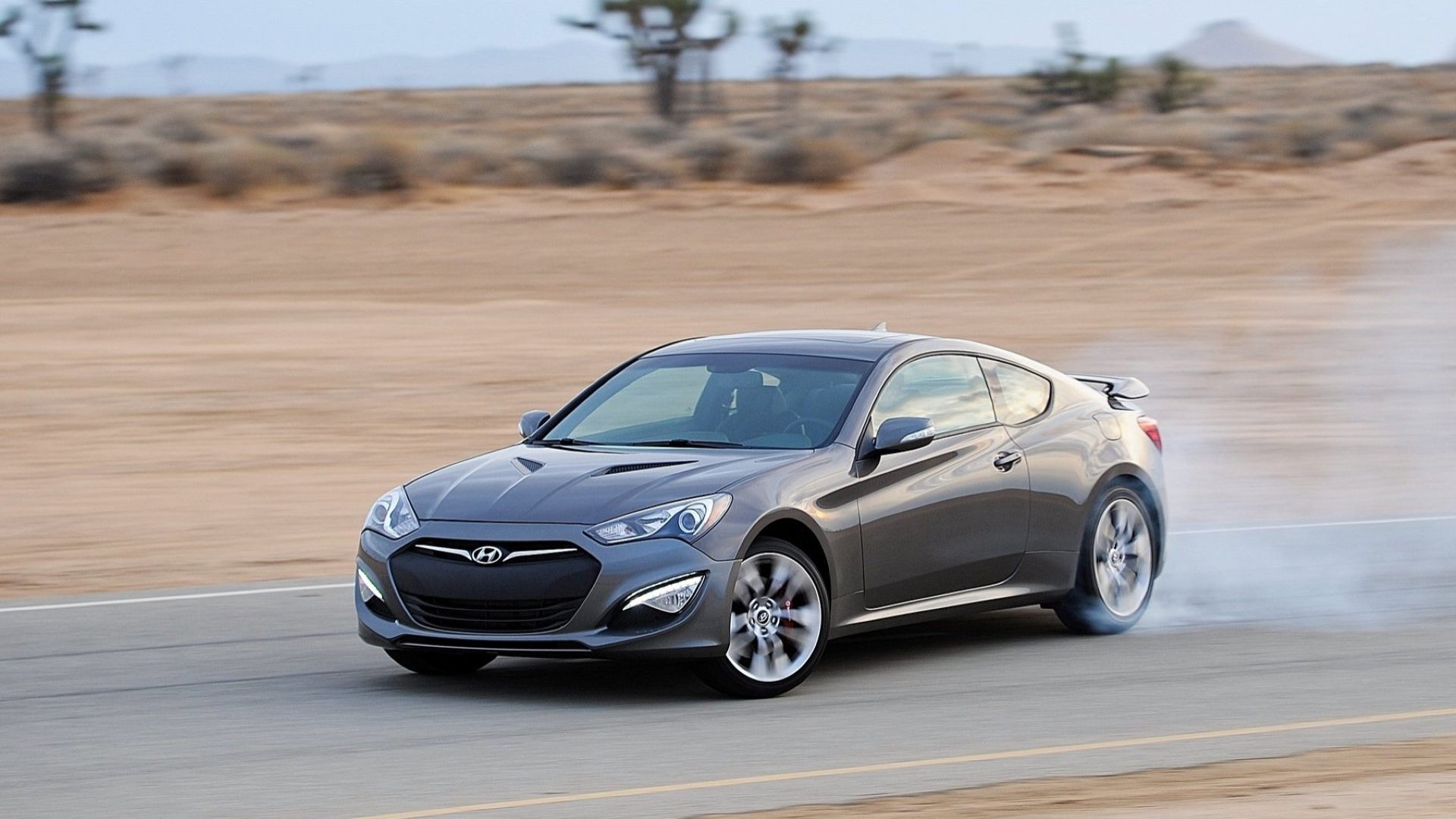 Uma foto de ação de um Hyundai Genesis Coupe 2013 deslizando em uma esquina