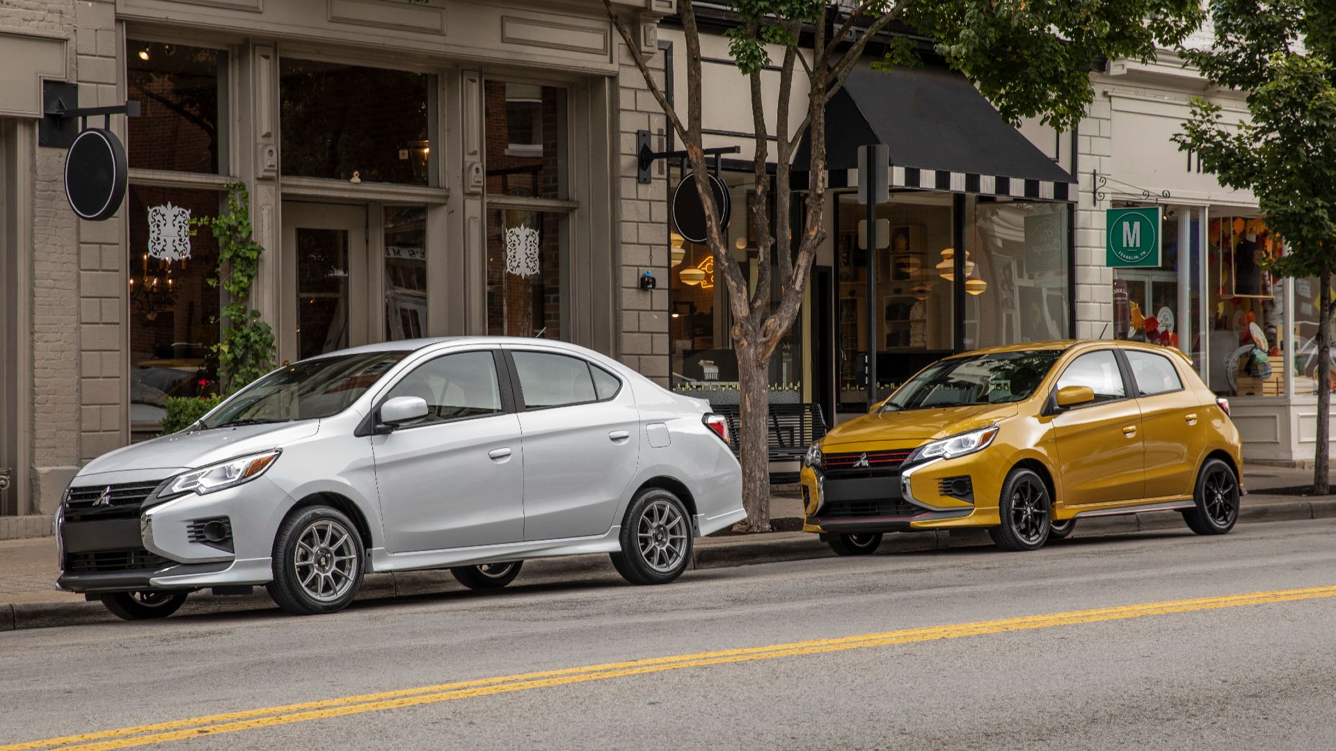 Une Mitsubishi Mirage White Diamond garée devant un Mirage Sand Yellow le long du trottoir