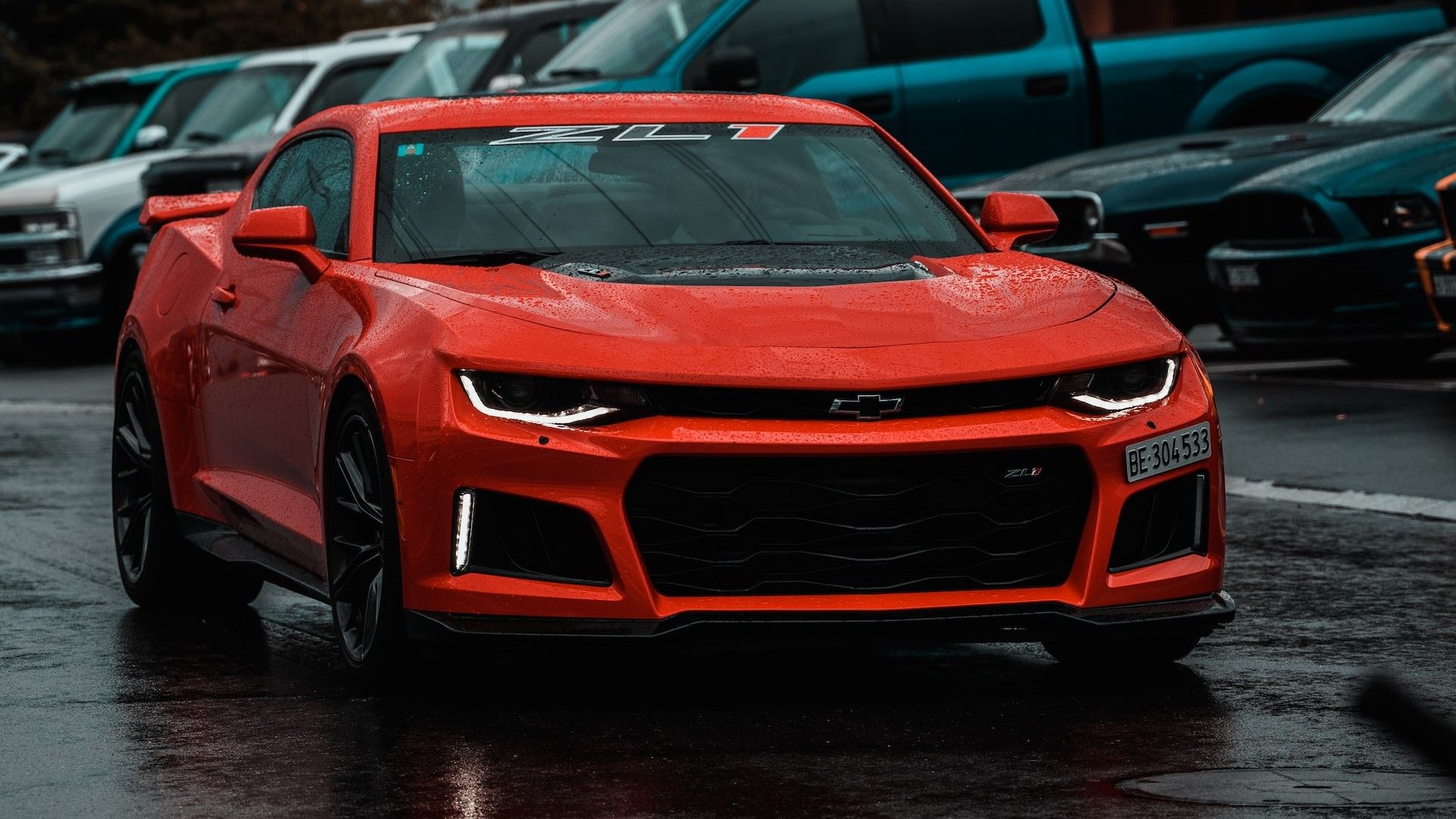Red Chevrolet Camaro ZL1 front passenger 3/4 view driving on a rainy day.
