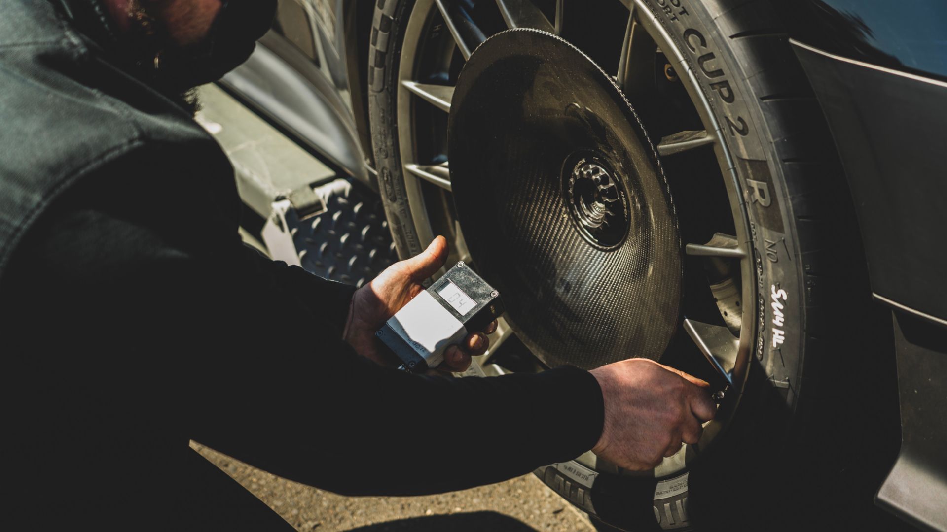 Um engenheiro verificando a pressão dos pneus do Porsche 911 GT2 RS MR 2021