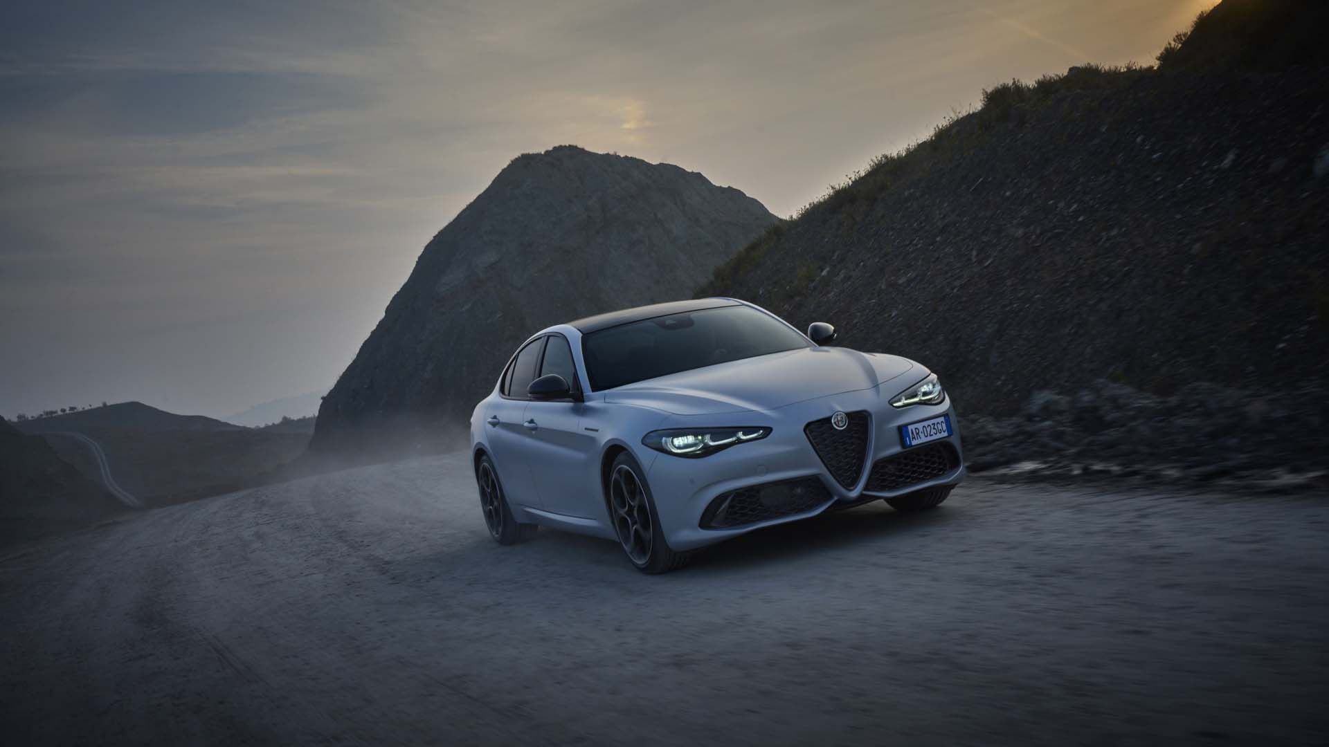 Alfa Romeo Giulia dirigindo em estrada empoeirada