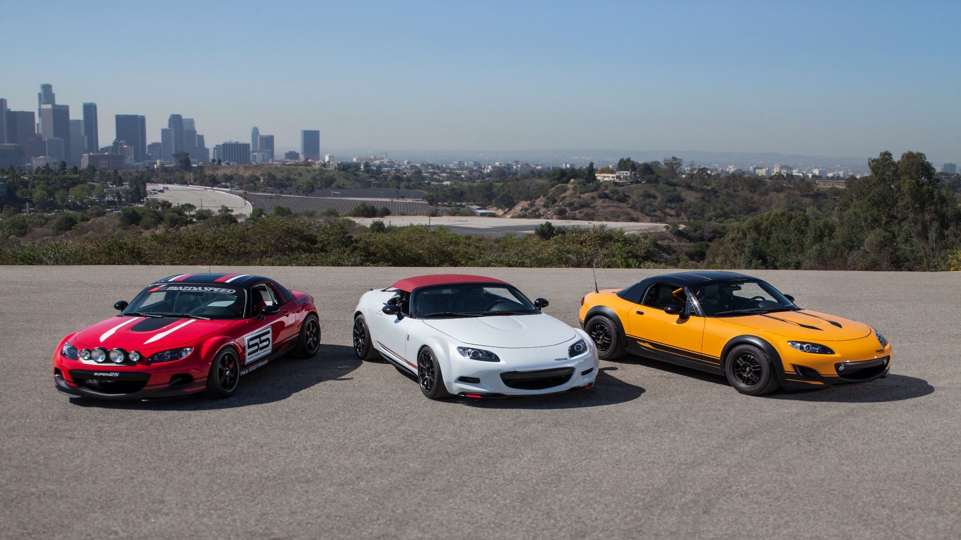Três Mazda Mx-5 Miata lado a lado, vermelho, branco e amarelo
