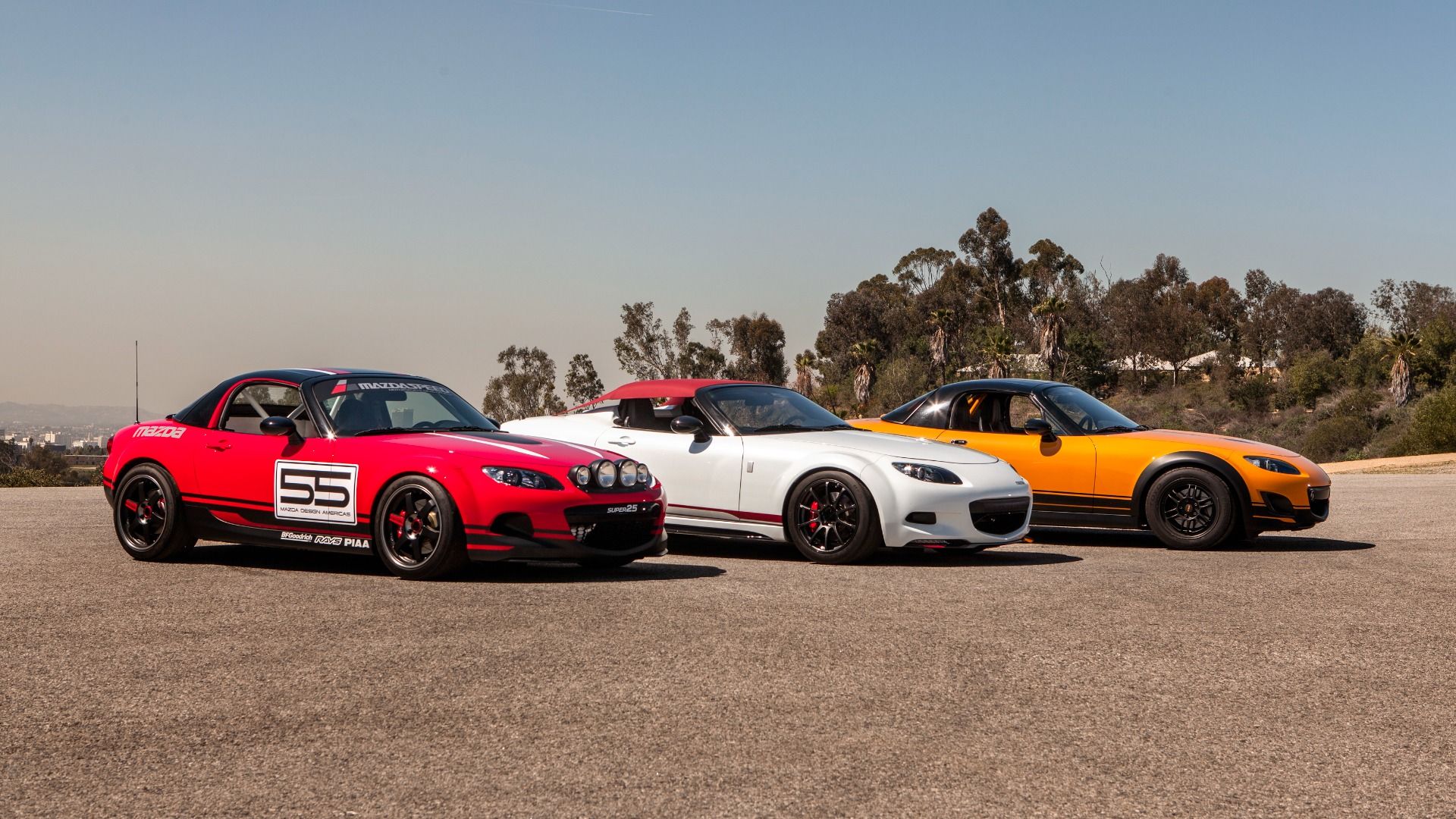 Três Mazda Mx-5 do lado de Miata.  Vermelho, Branco, Amarelo