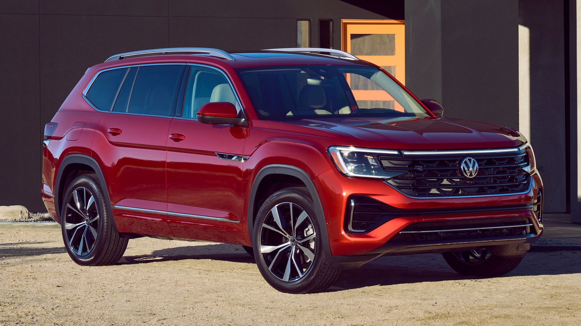 2024 VW Atlas SEL Premium R-Line featuring Aurora Red color shown outside a house in front three quarter angle