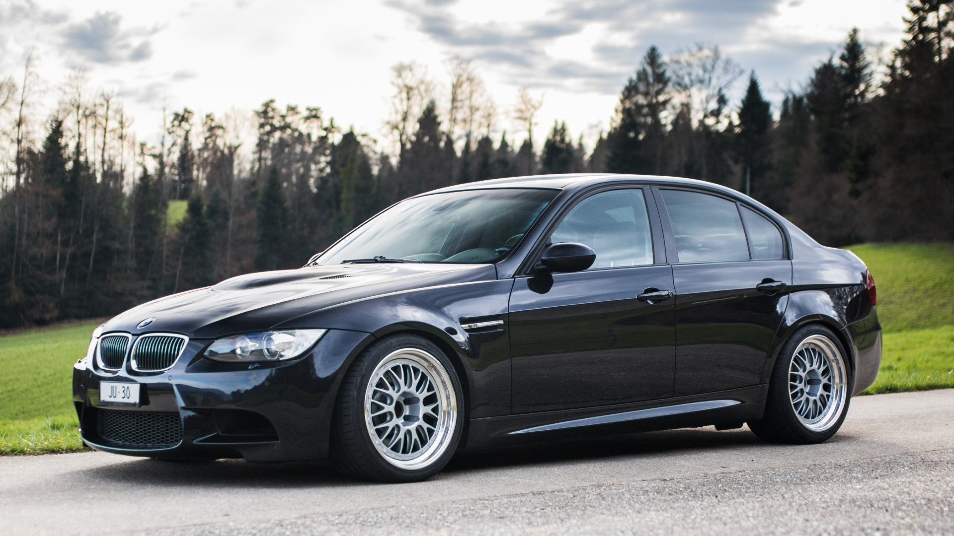 A Black 2013 BMW M3 parked on the road at a hill