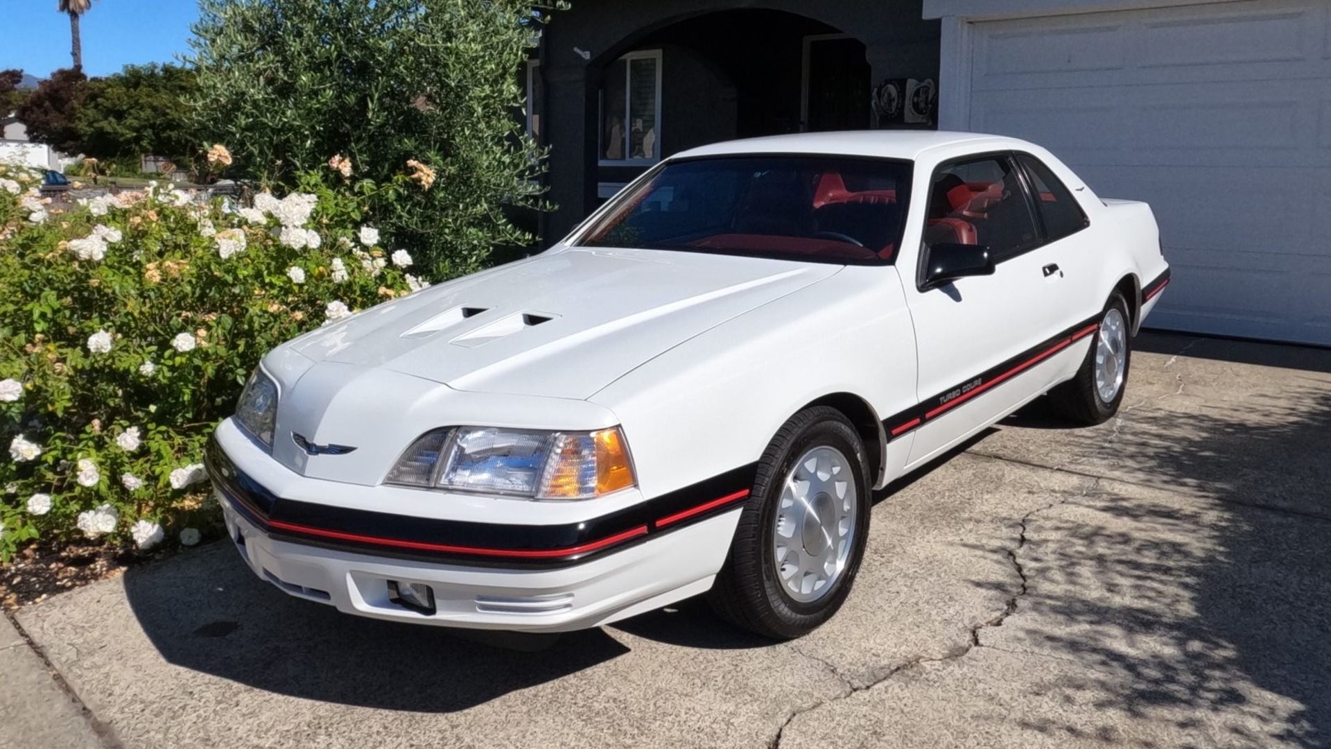 Um Ford Thunderbird Turbo Coupe 5 velocidades, branco, com detalhes em preto e vermelho, 1988