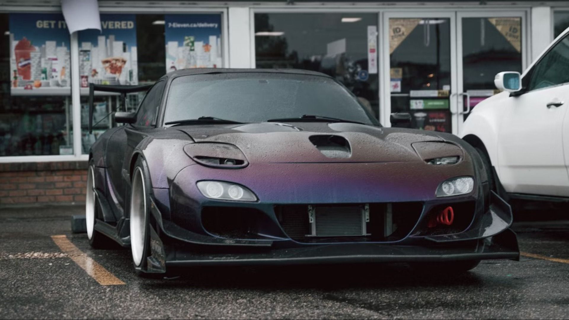 A beautiful wide body Mazda FD RX7 with an LS Swapped motor parked in front of a convenience store