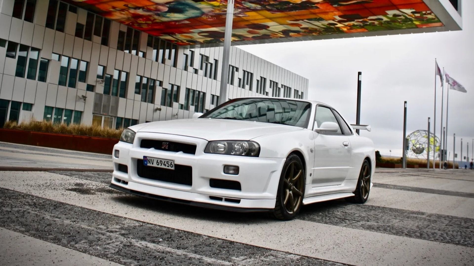 A white 1999 Nissan R34 Skyline GT-R parked on a cloudy day.