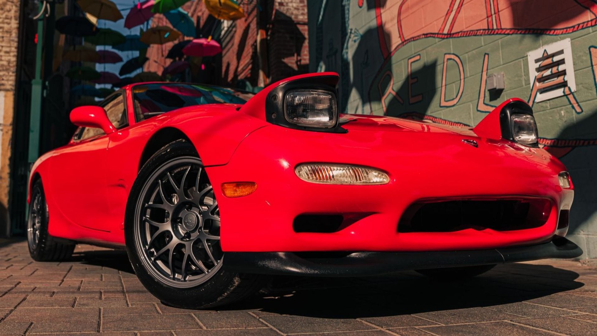 A red 1994 Mazda RX-7 5-Speed showing its sleek lines and iconic pop-up headlights.