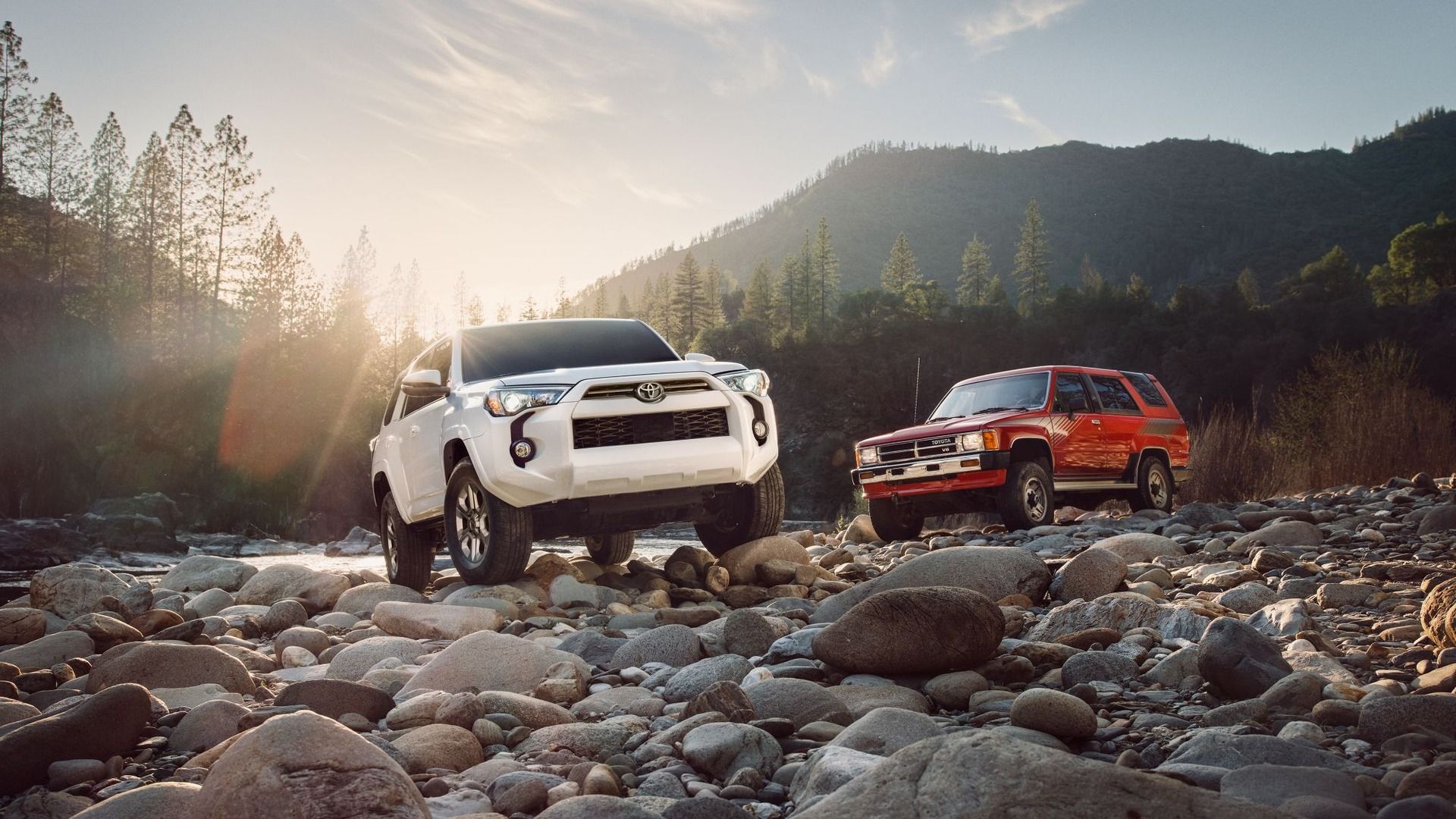 A white 2024 Toyota 4Runner and classic red 4Runner parked on rocks