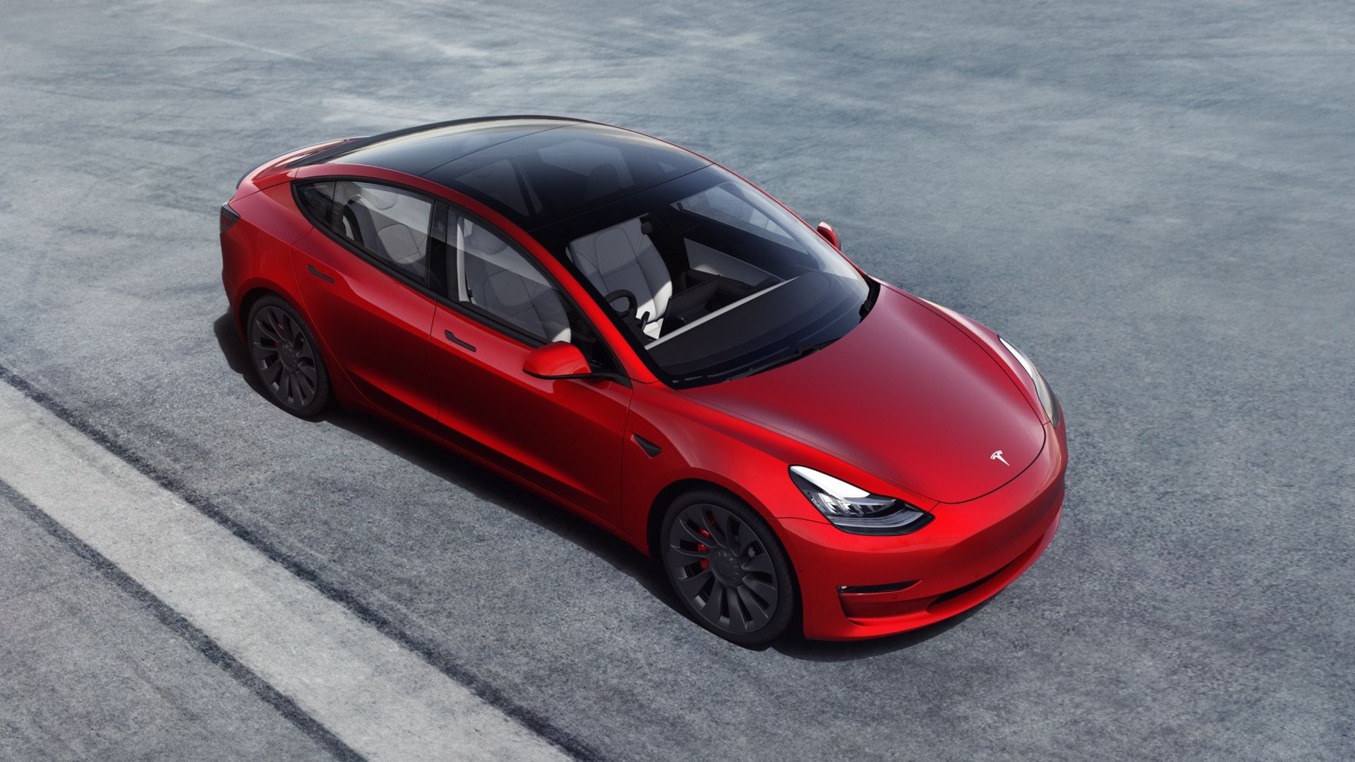 A red Tesla Model 3 seen from above