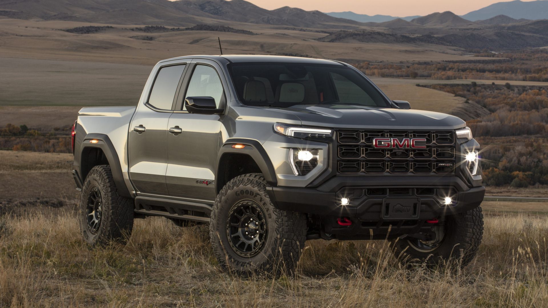 2024 GMC Canyon AT4X AEV in gray posing in field in front of mountain range