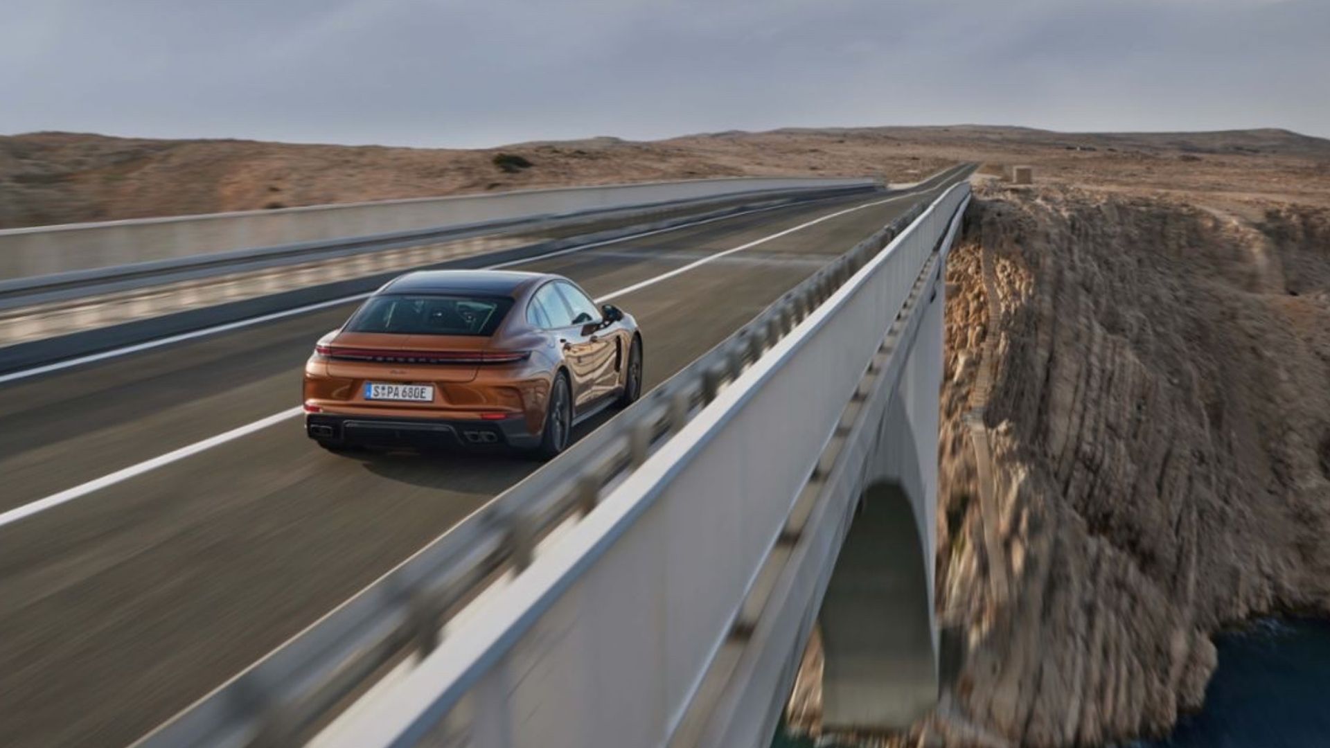 2024 Porsche Panamera Turbo E-Hybrid in gold posing on bridge over river