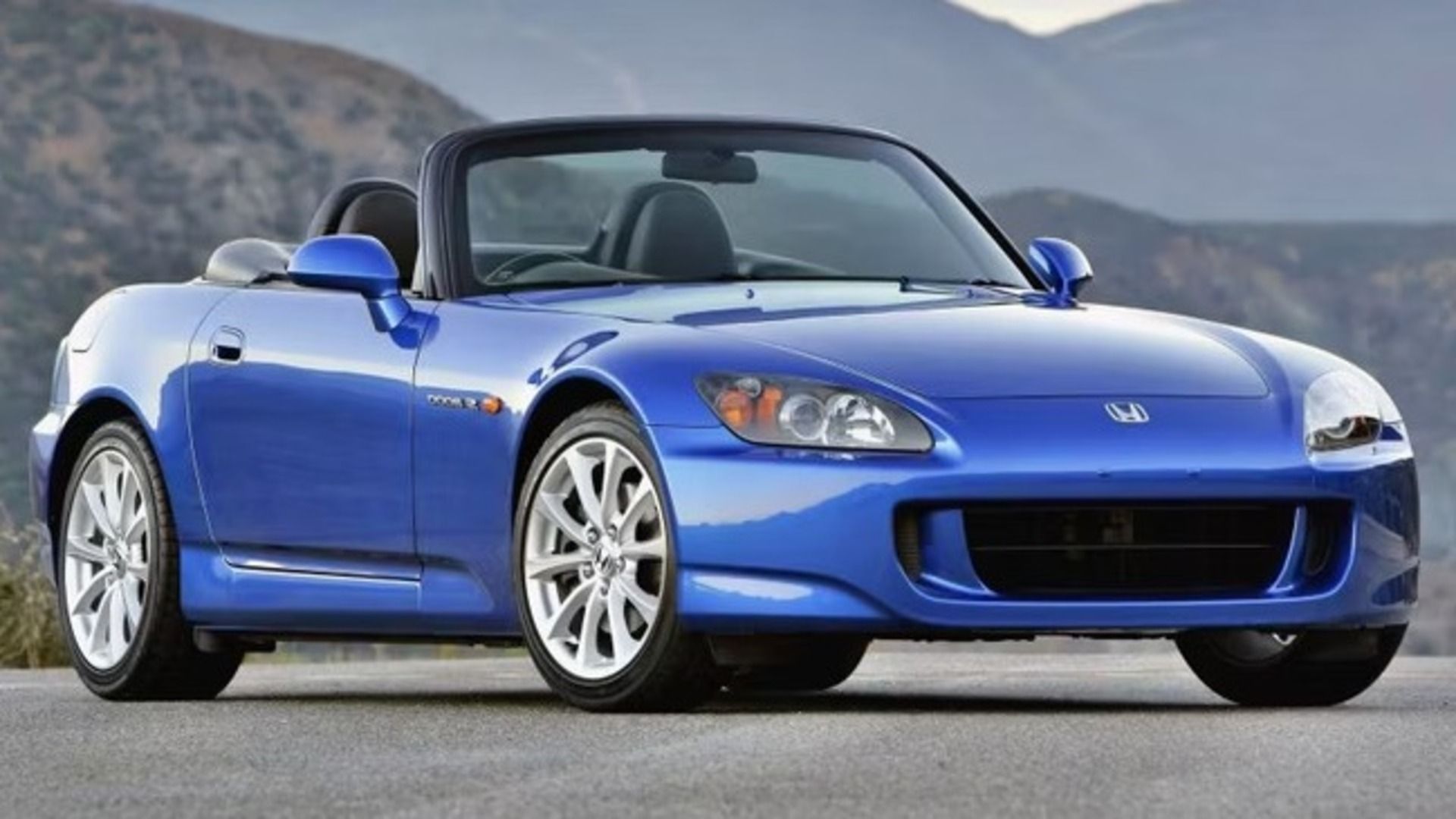 Honda S2000 AP1 finished in Blue stopped on a road infront of mountains.
