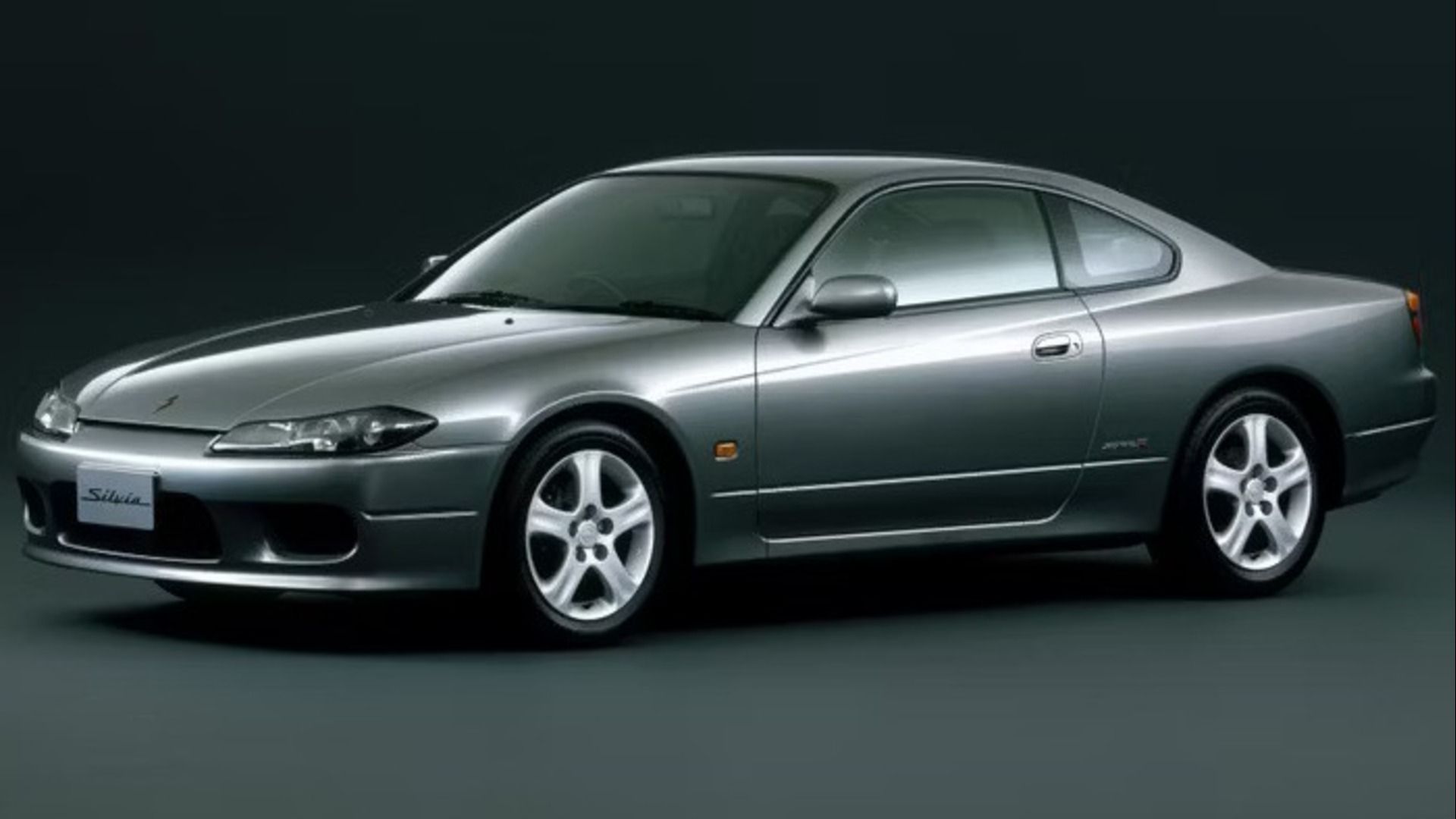 O Nissan S15 colorido em Pewter estacionado em uma sala preta.