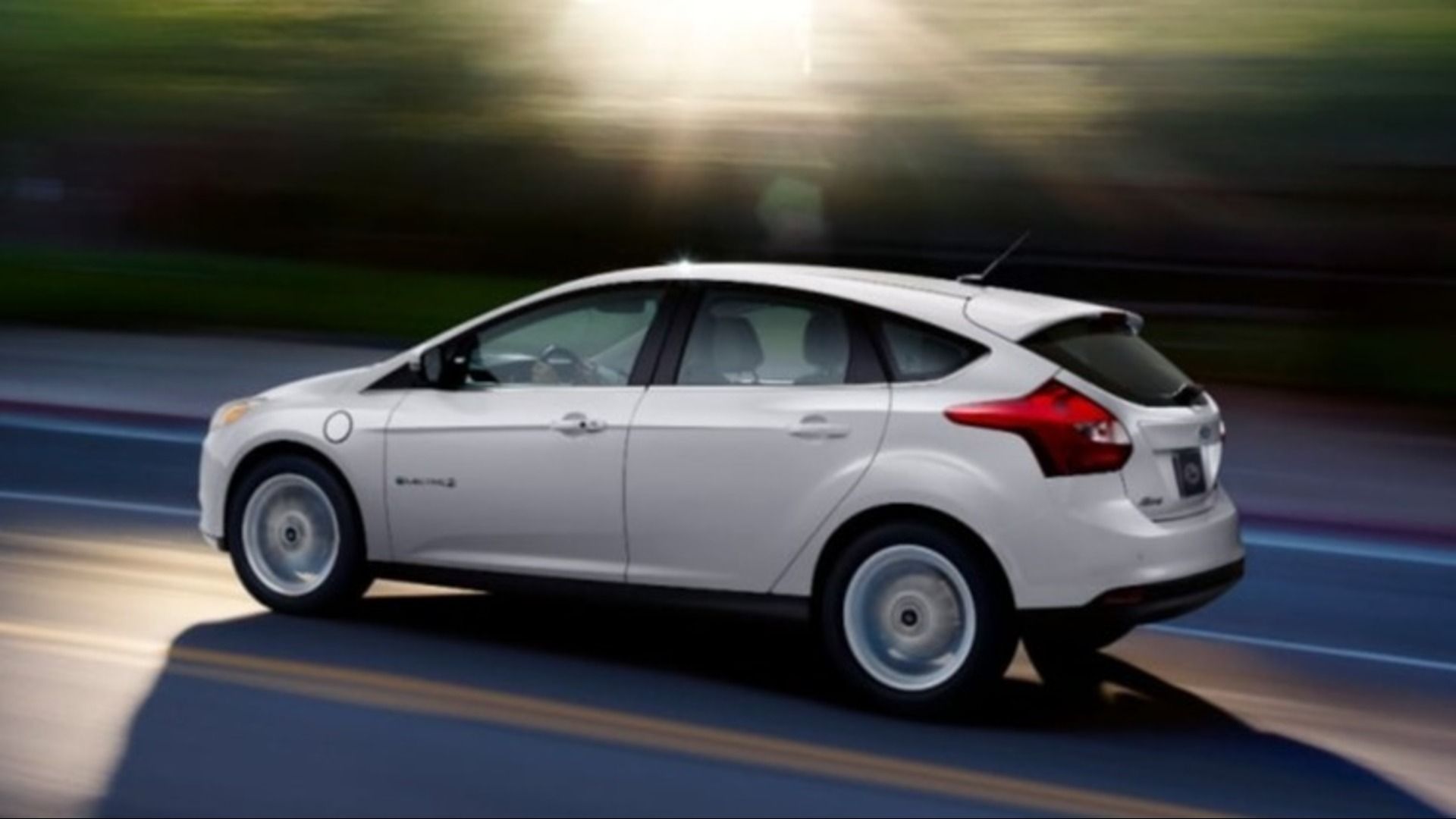 A white Ford Focus Electric driving at speed on a dual carriageway.