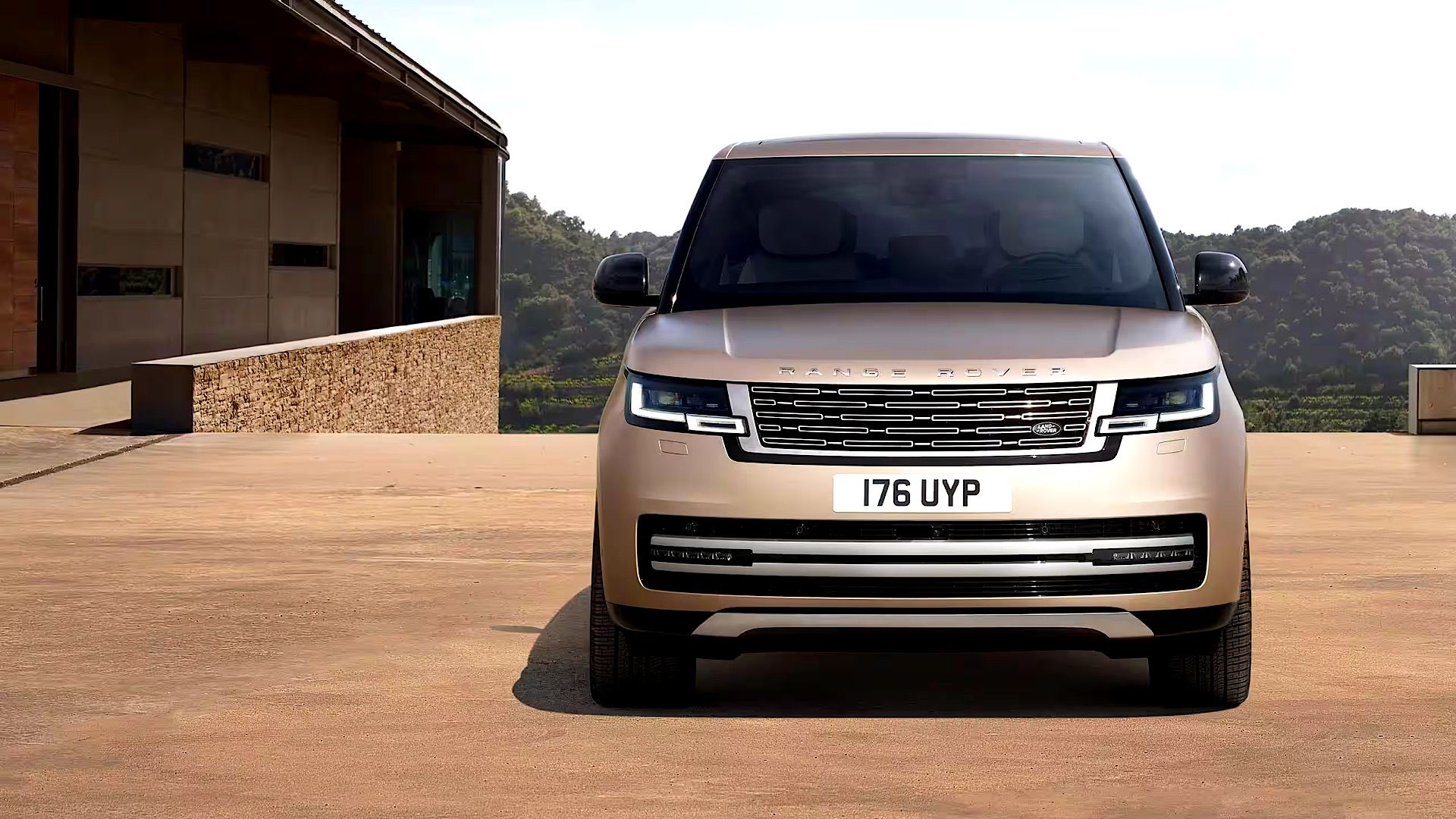 2024 Land Rover Range Rover in copper posing outside of luxury home