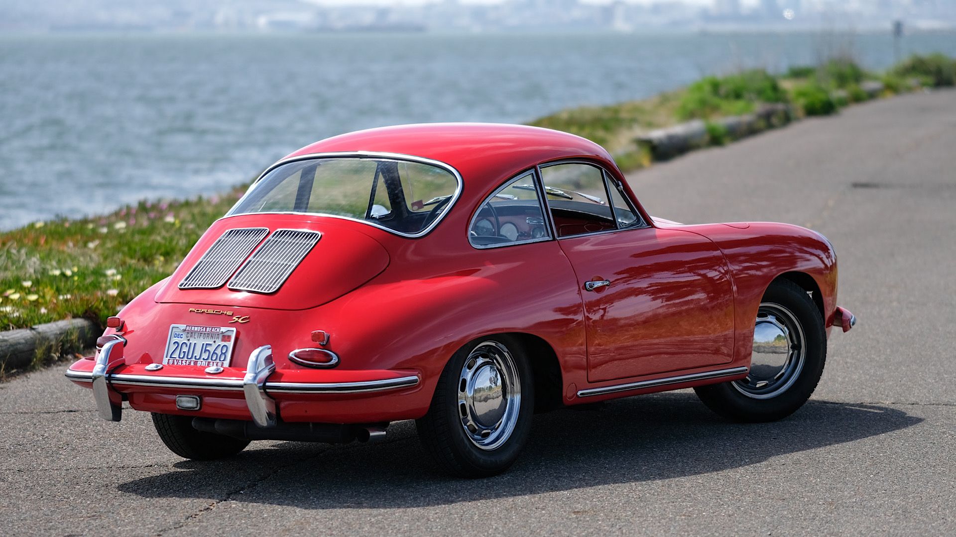 Porsche 356 1964 em vermelho posando em estrada costeira